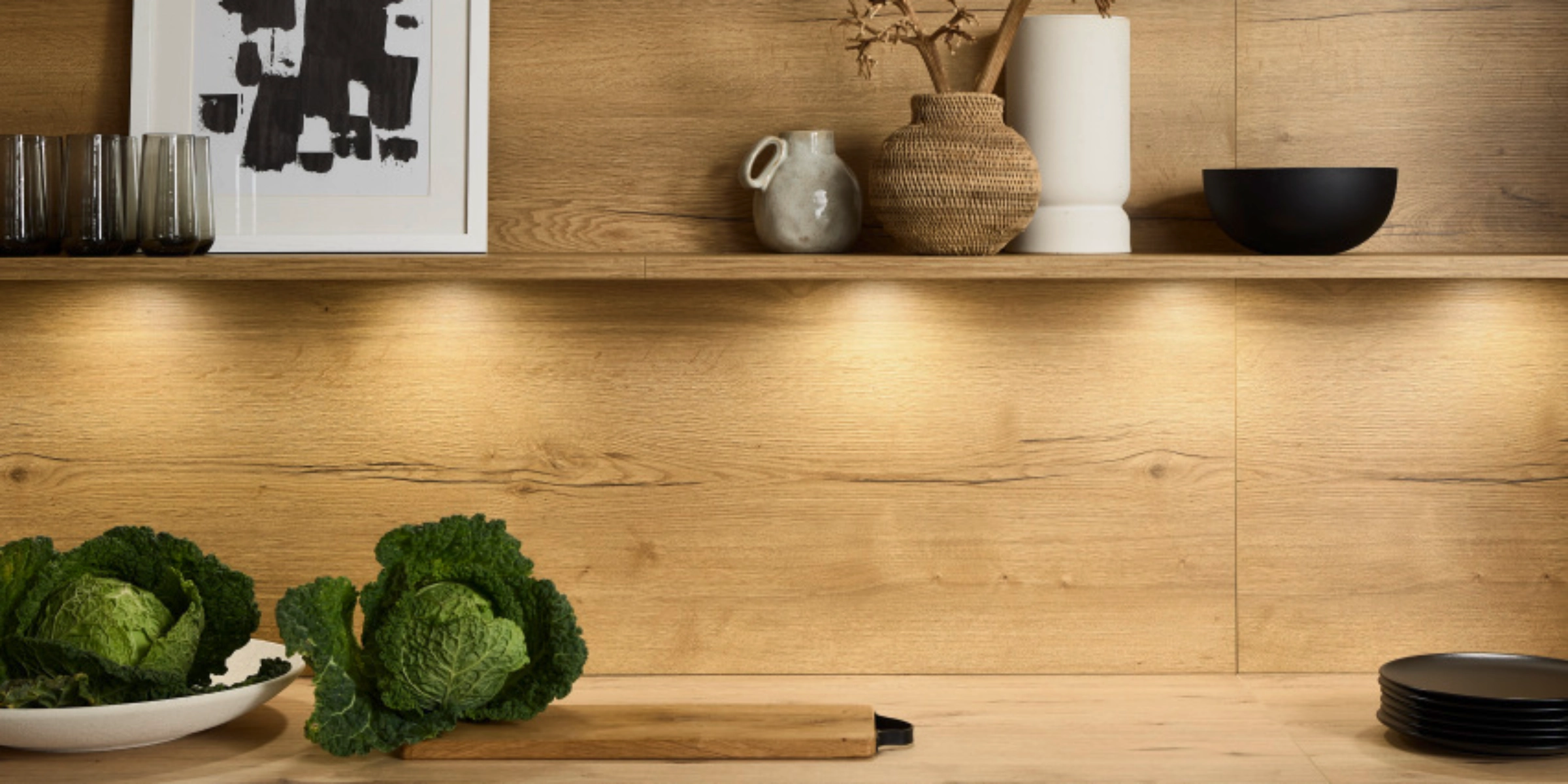Eine moderne Küche mit Holzoptik, Regalen und Dekorationen, gestaltet von Nolte Küchen.