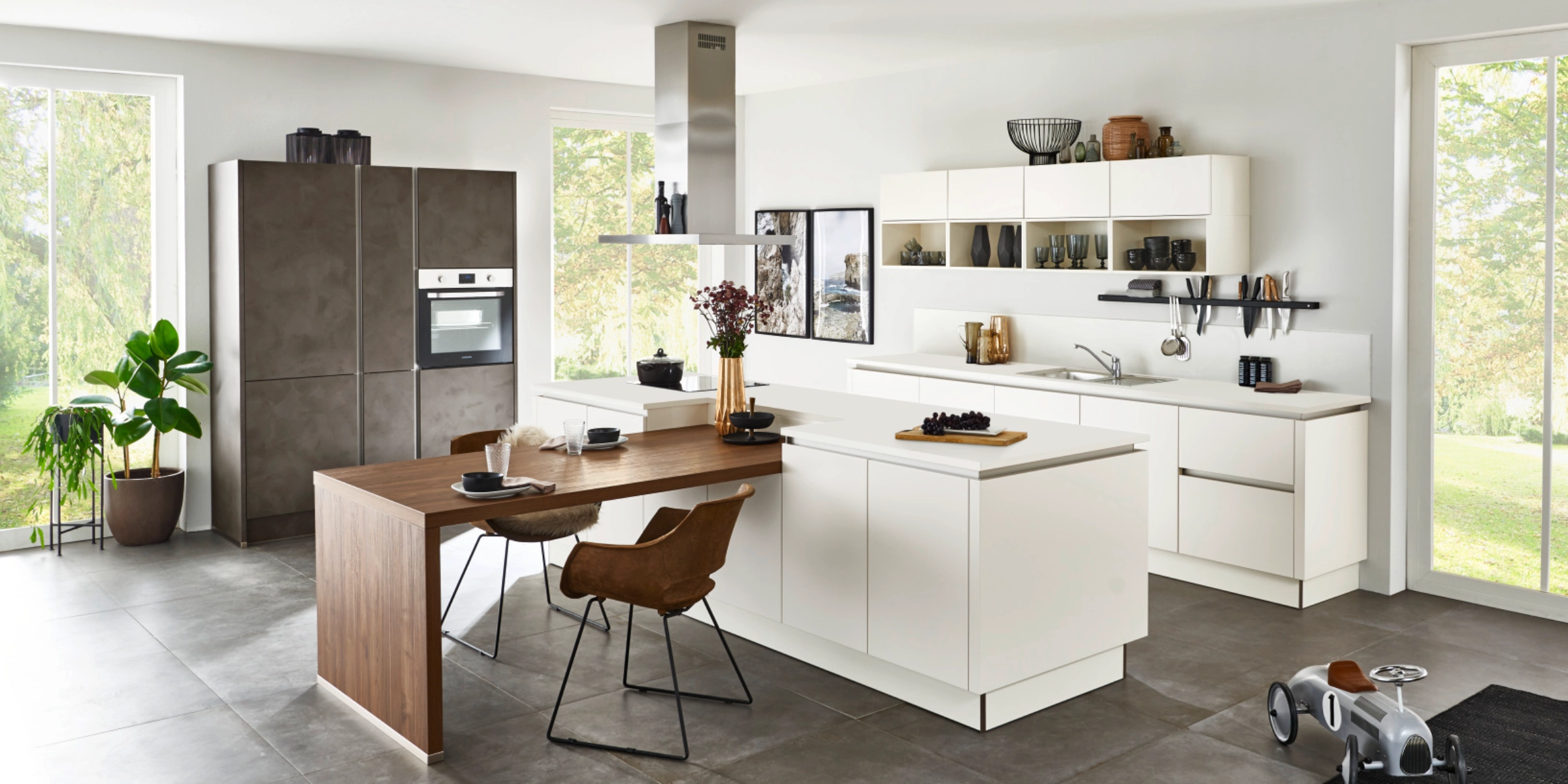 Moderne Nolte keuken met fronten in SOFT LACK Magnolia softmatt en PORTLAND Zement Anthrazit, gecombineerd met houten eettafel en royaal ruimteconcept in lichte woonatmosfeer.