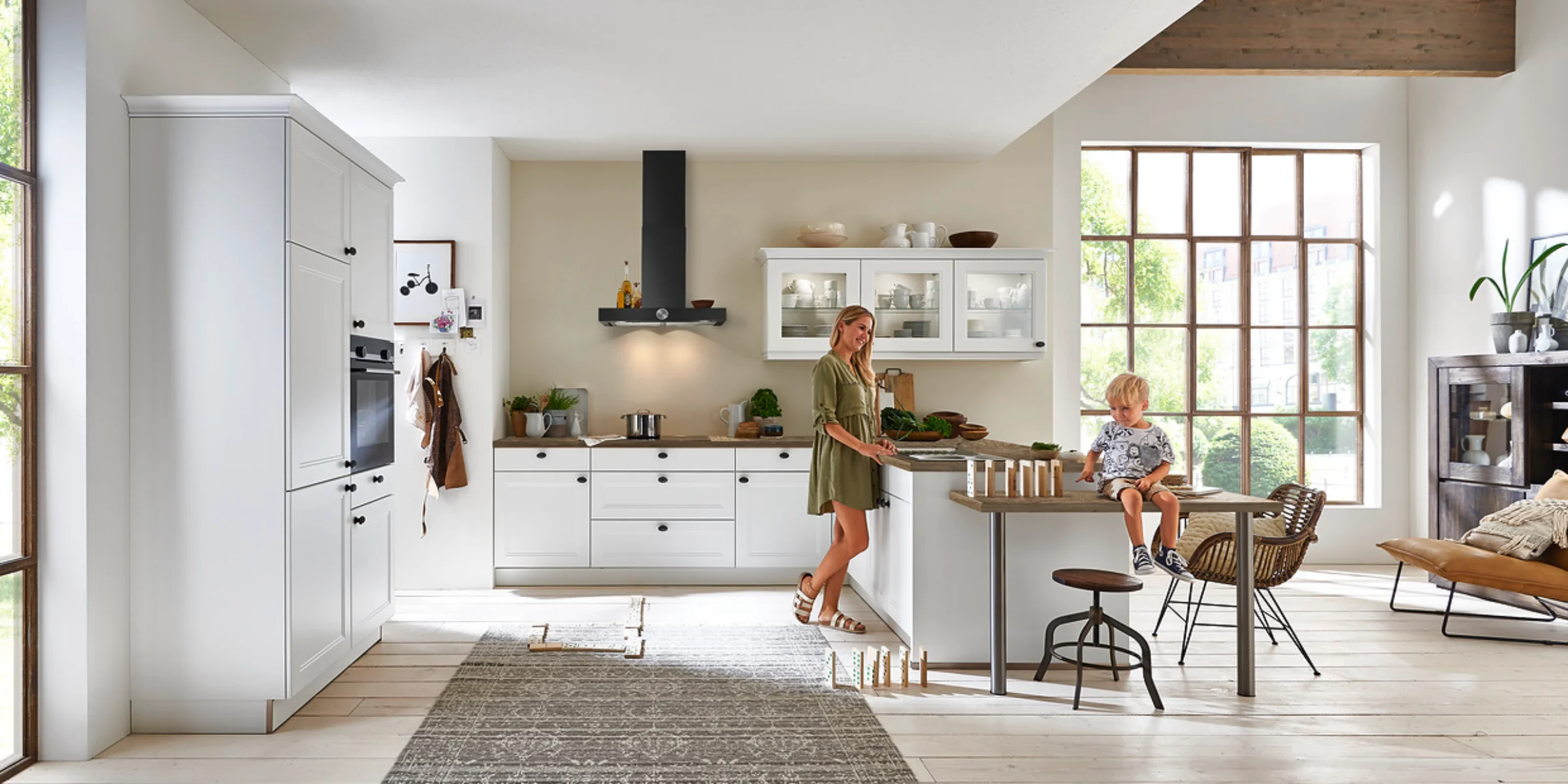 Helle Küche im urbanen Landhausstil in Premiumweiß mit Holzarbeitsplatte und schwarzen Griffen von Nolte Küchen – gemütliches Design mit modernen Akzenten.