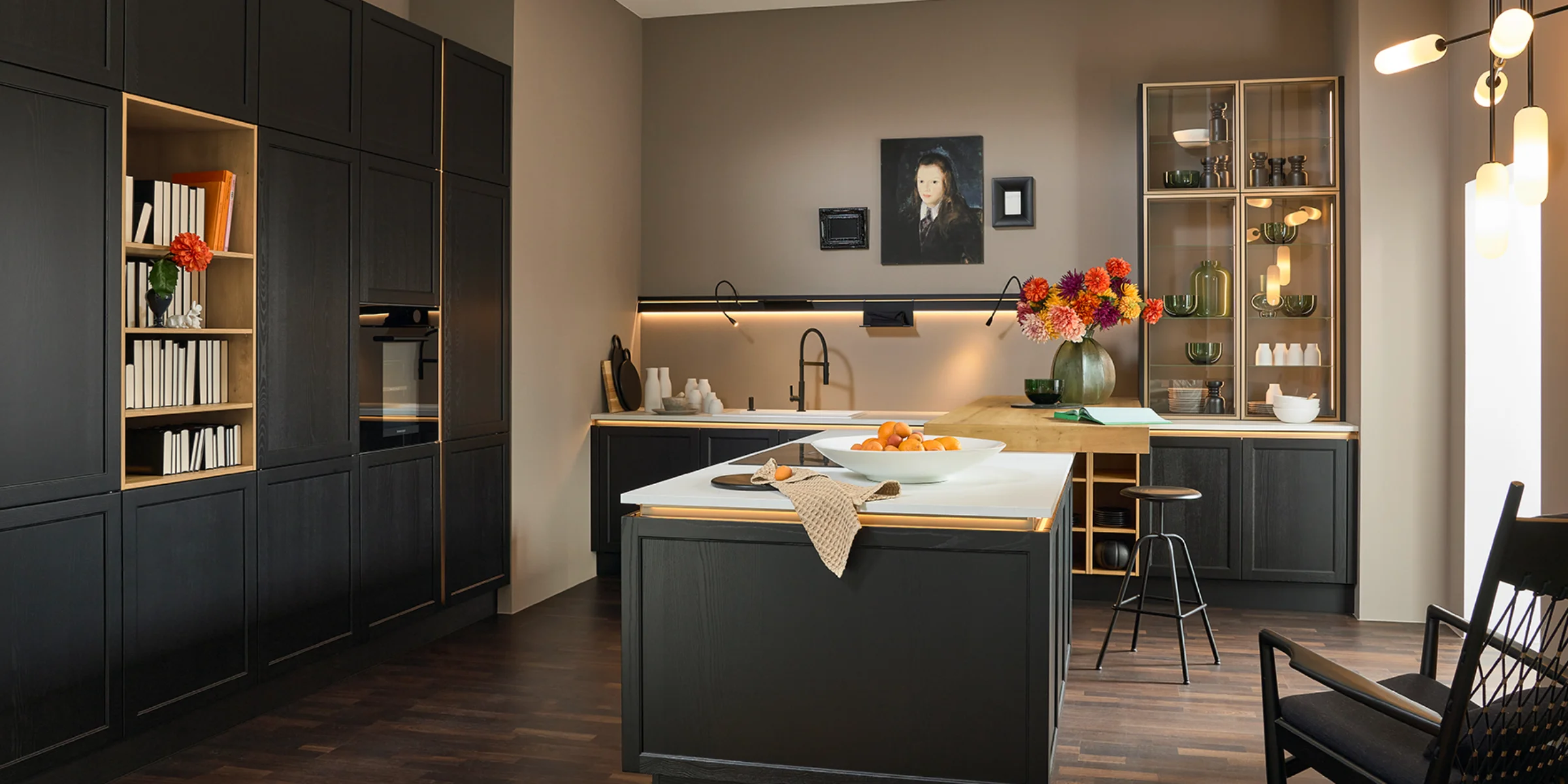 Eine moderne Küche mit dunklen Schränken und zentraler Kochinsel von Nolte Küchen.