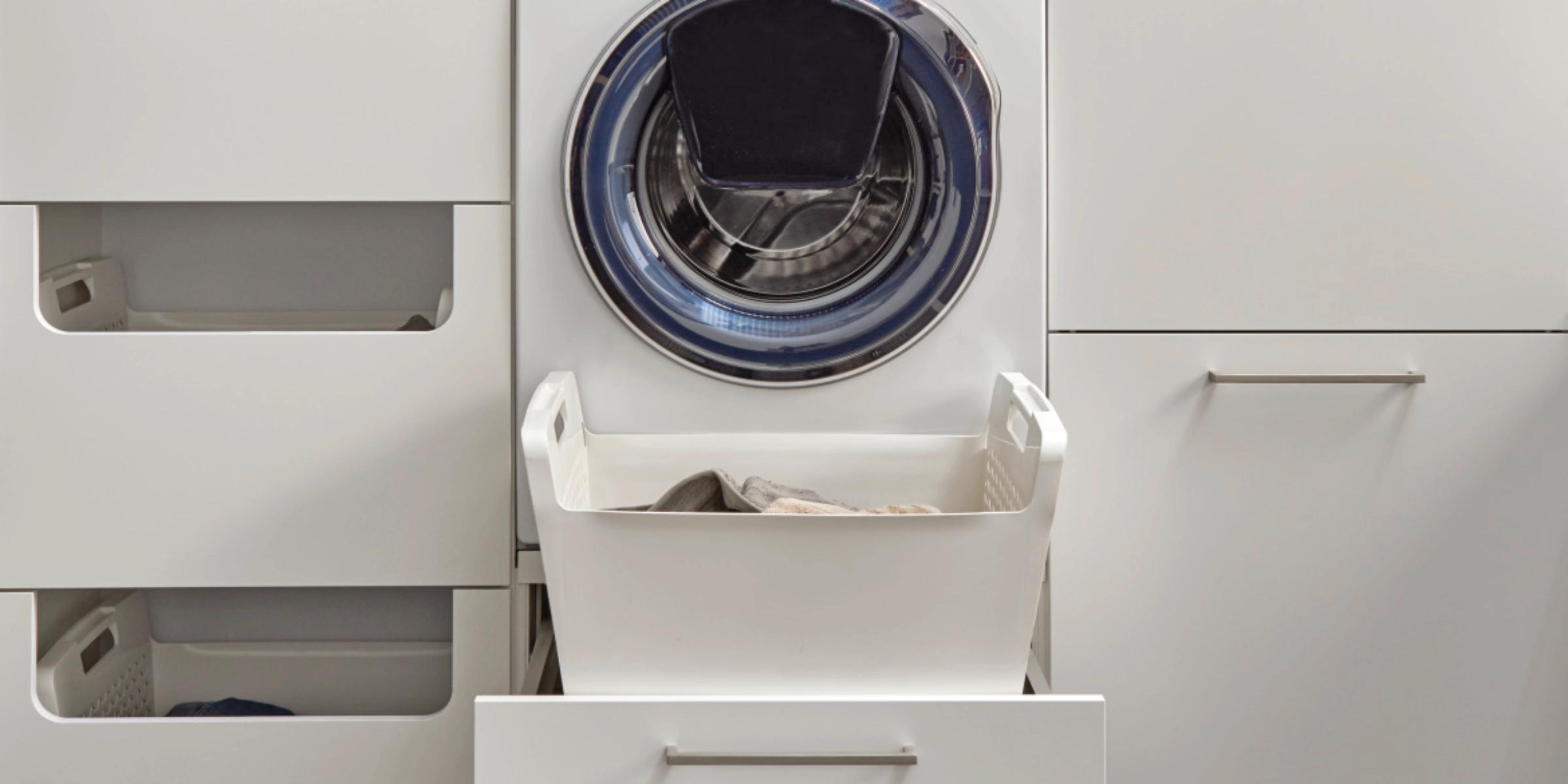 Une buanderie moderne avec machine à laver et rangement, conçue par Nolte Utility Rooms.