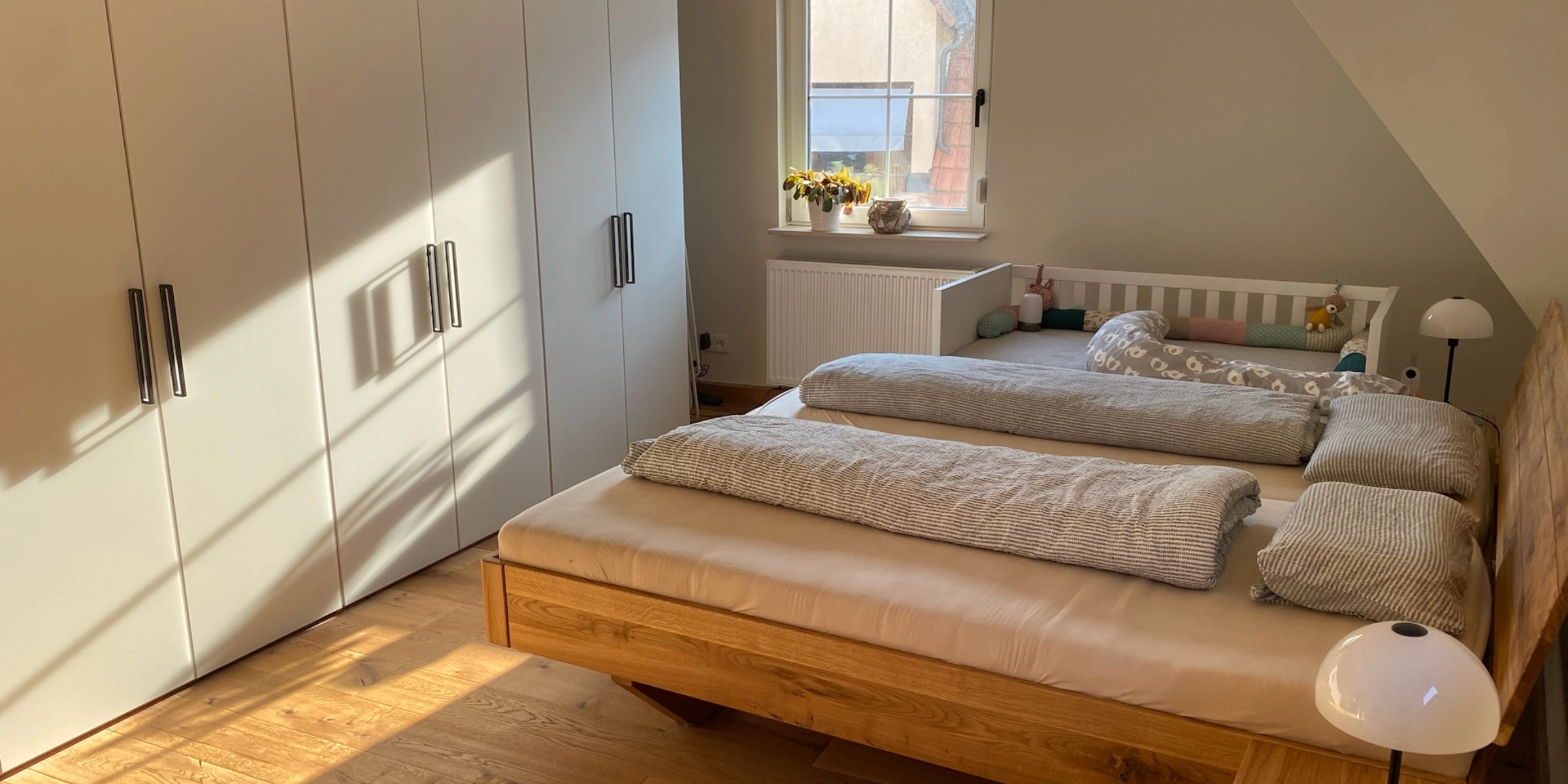 Une chambre avec lit double et armoire, éclairée par la lumière du soleil, de Nolte Living.
