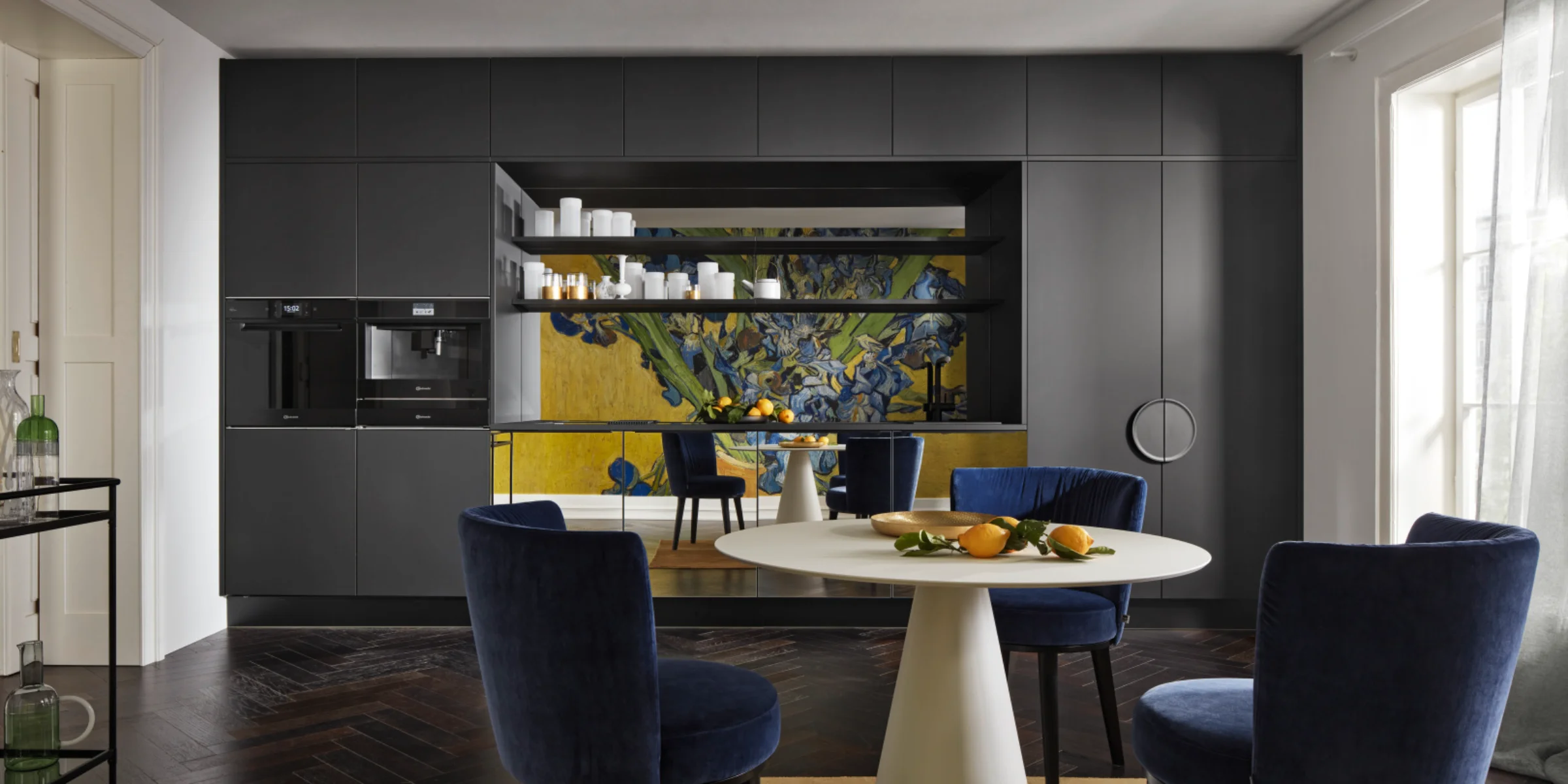 A modern kitchen with dark cabinets and a round table, designed by Nolte Kitchen.