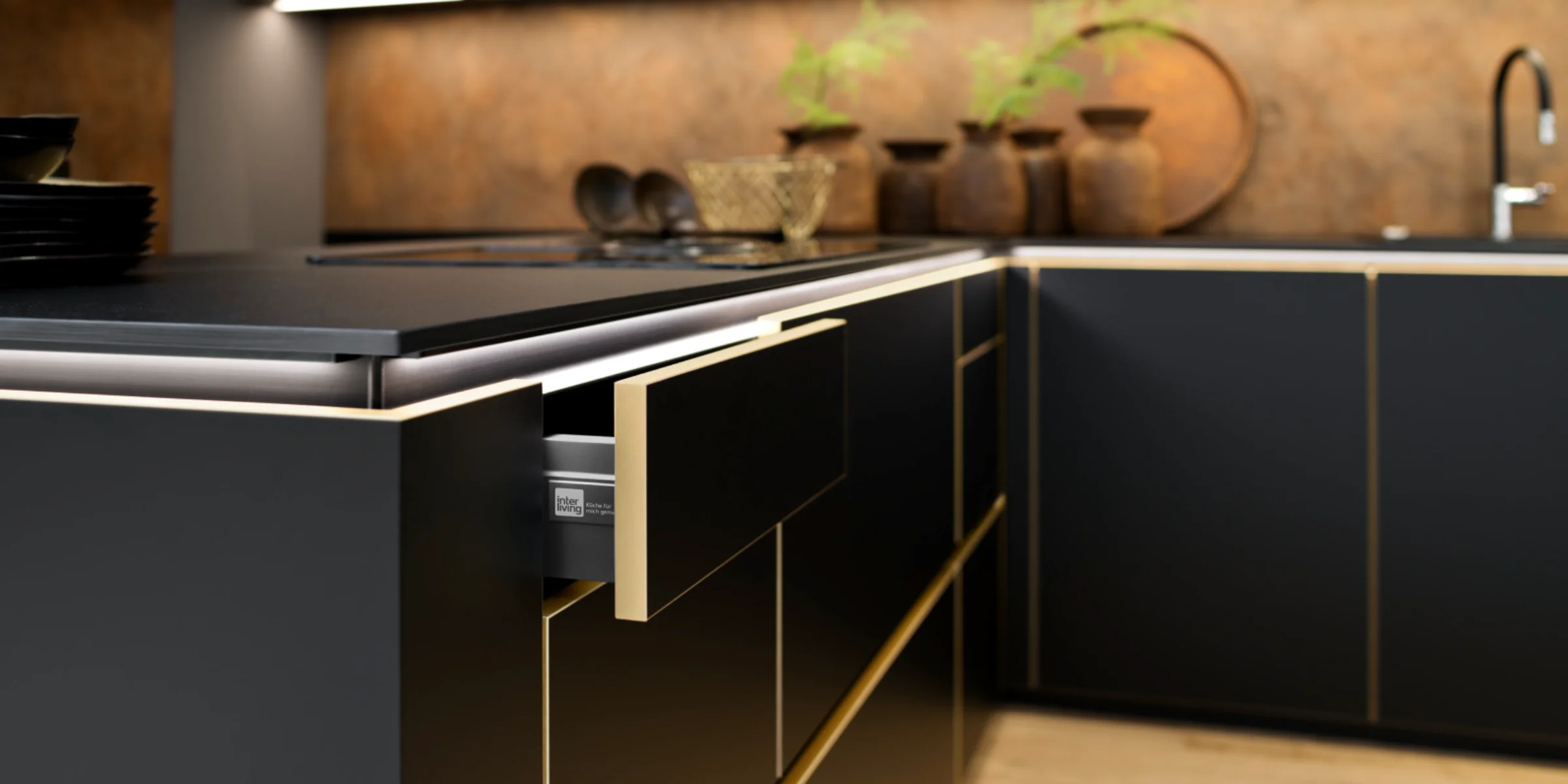 Eine moderne schwarze Küche mit goldenen Akzenten und Pflanzen. Nolte Küchen.