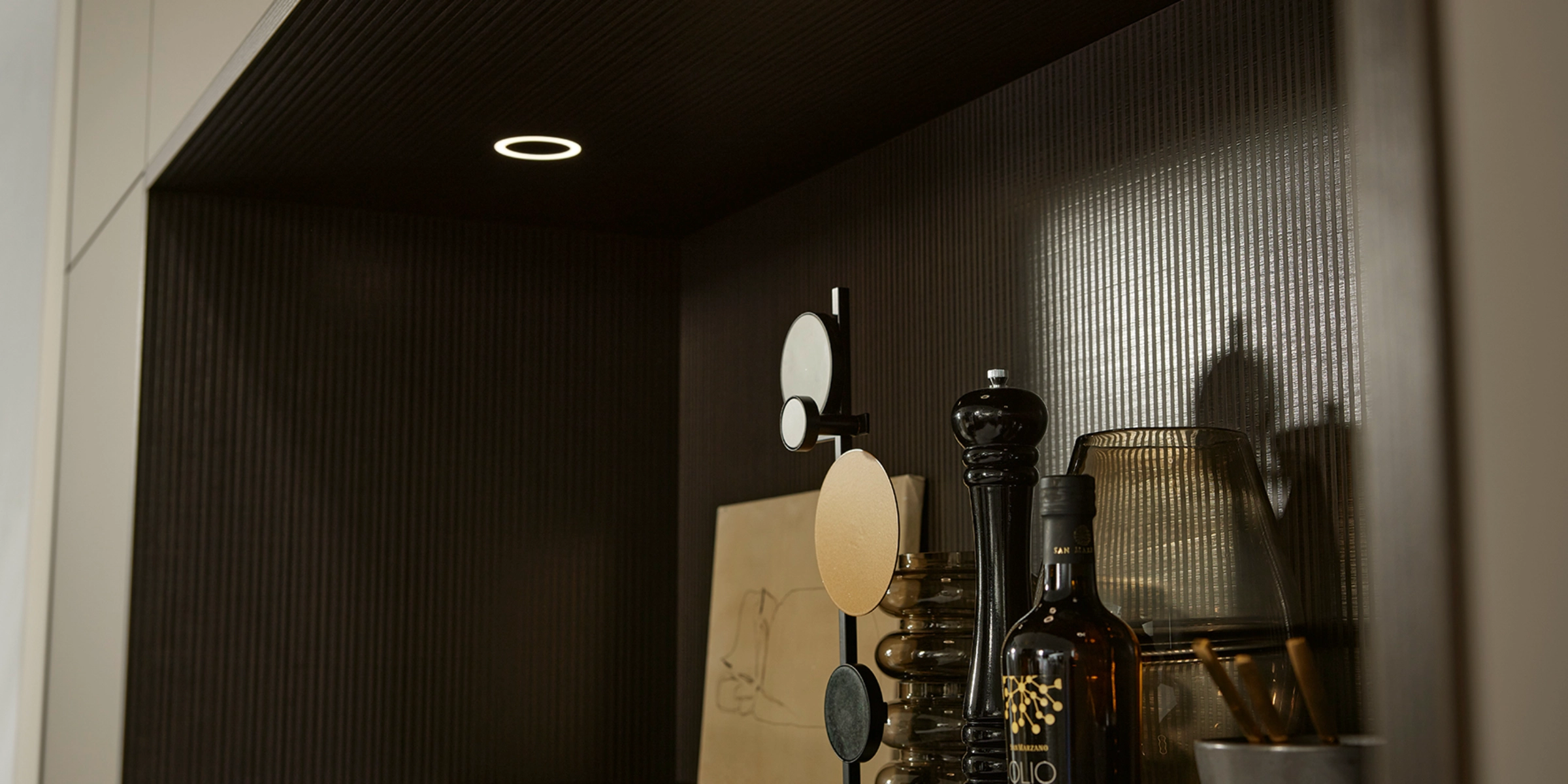Une étagère avec épices et objets déco, éclairée par des spots encastrés. Nolte Kitchen.