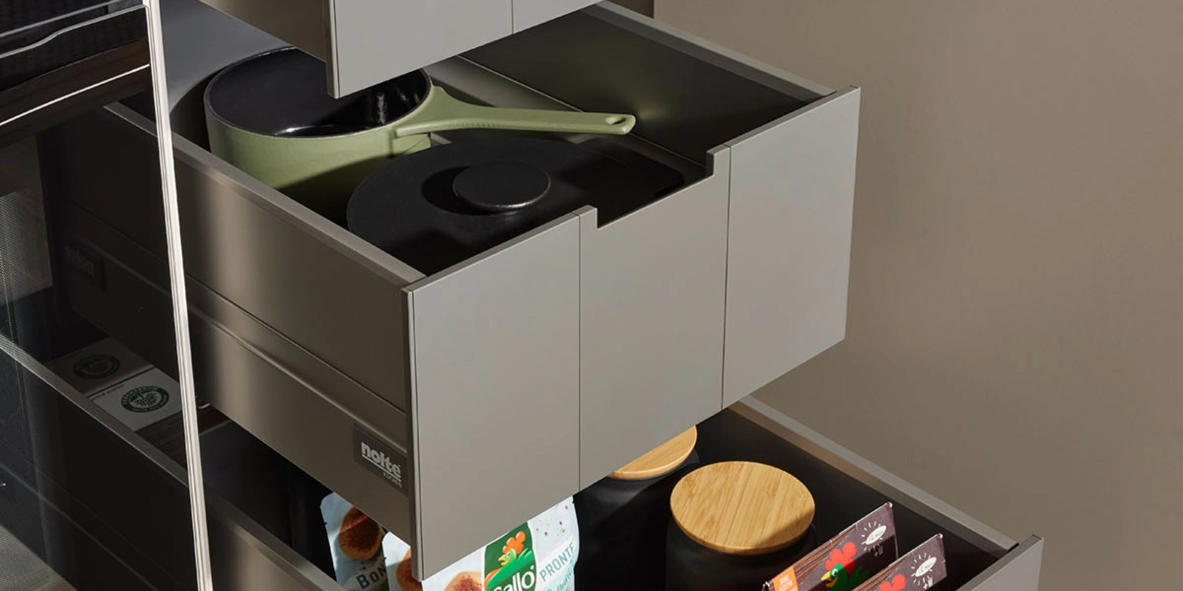 Open kitchen drawers with organized contents in a modern Nolte kitchen.