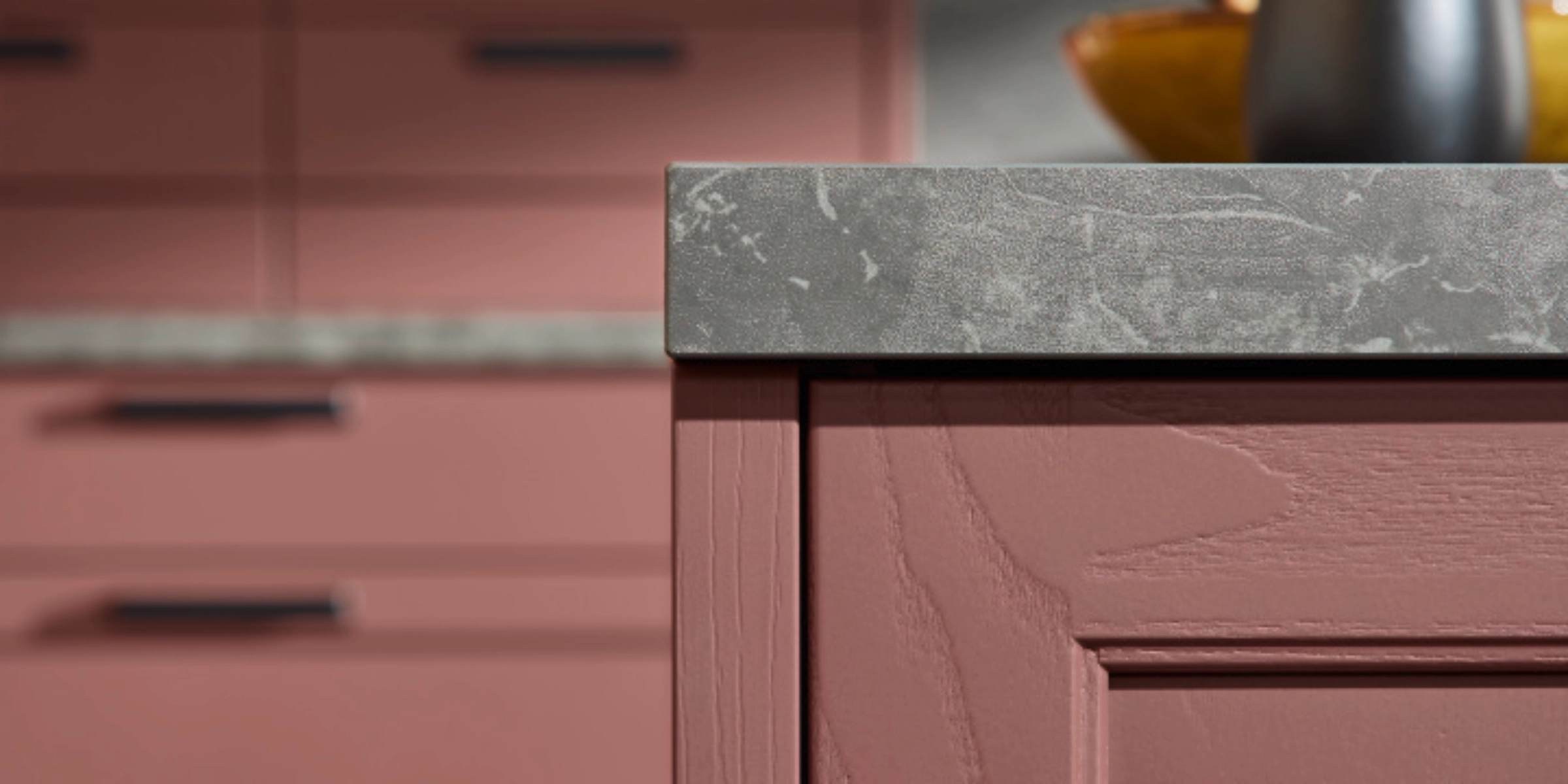 Une cuisine élégante avec des armoires roses et un plan de travail gris, présentée par Nolte Kitchen.
