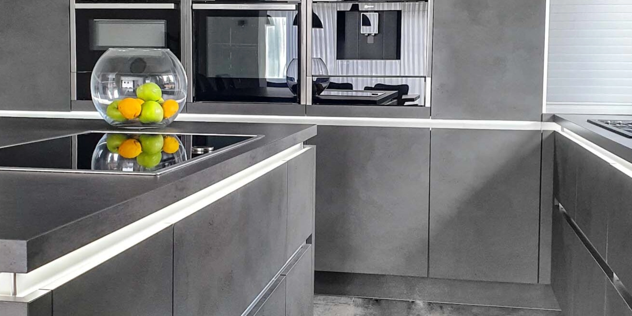 Cuisine moderne avec armoires grises et corbeille de fruits sur le plan de travail de Nolte Kitchen.