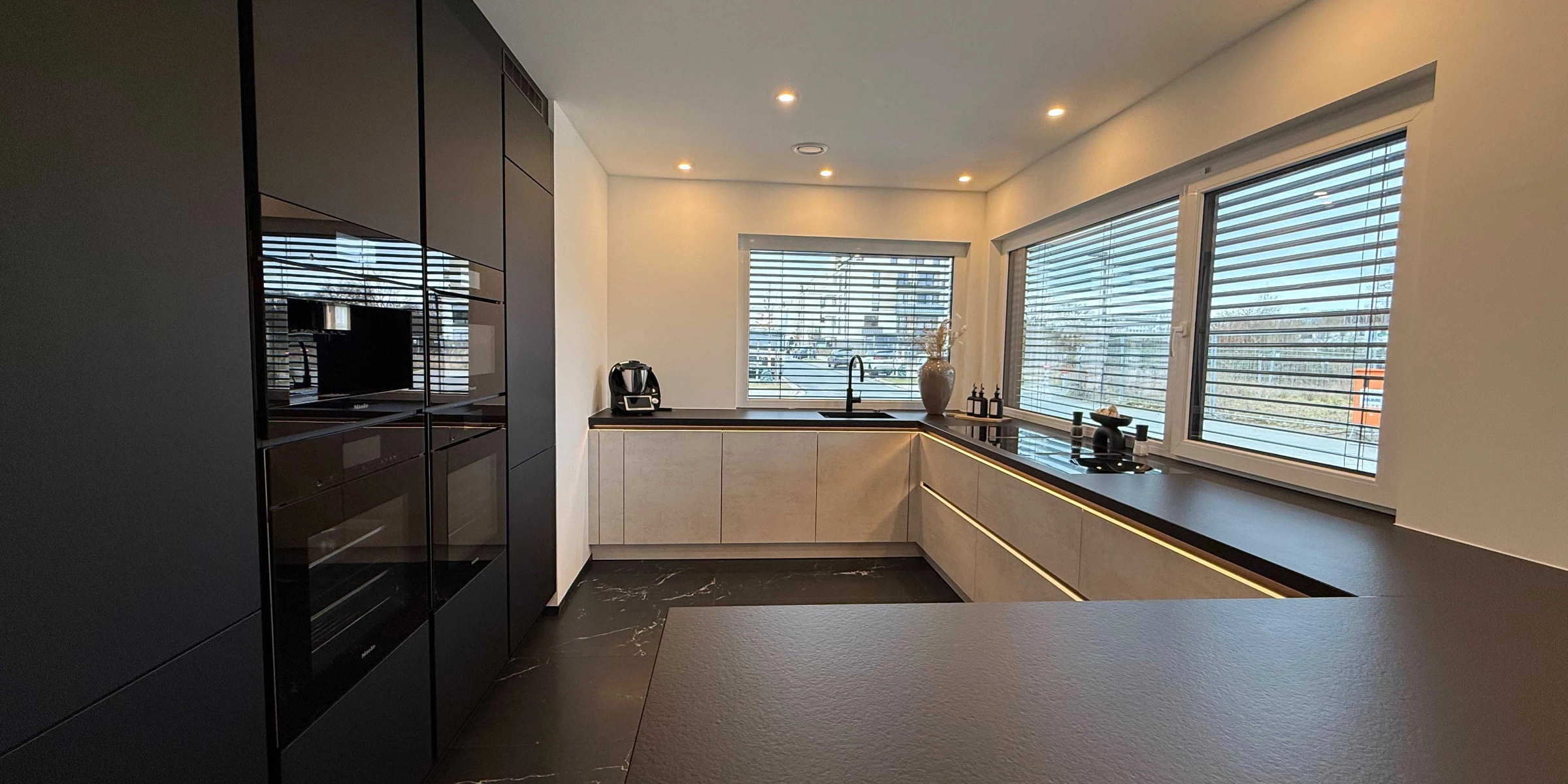 Une cuisine moderne avec des armoires sombres et de grandes fenêtres, Nolte Kitchen.