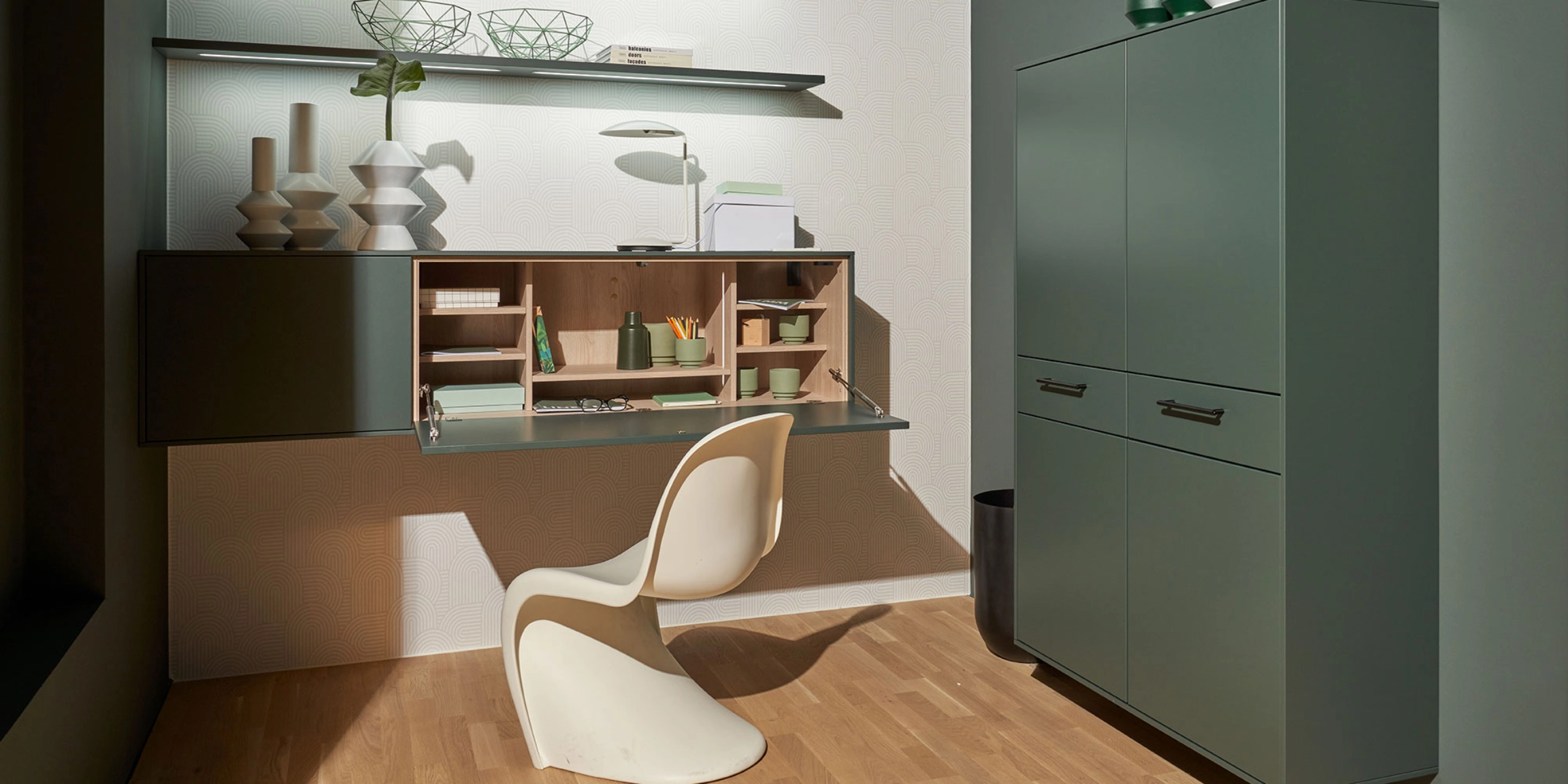 Un espace de travail élégant avec étagère et armoire modernes en vert, partie de Nolte Living.