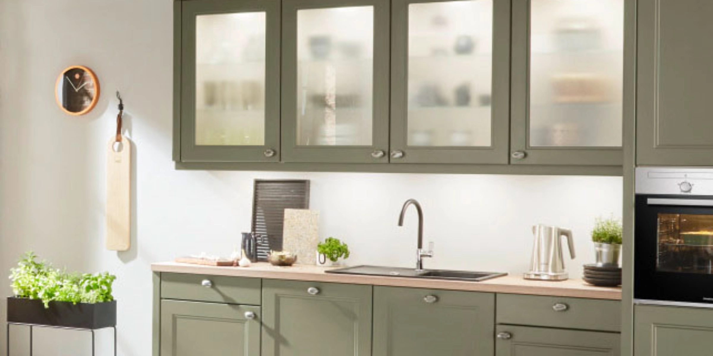 Una cucina moderna con armadi verdi e decorazioni. Nolte Kitchen.