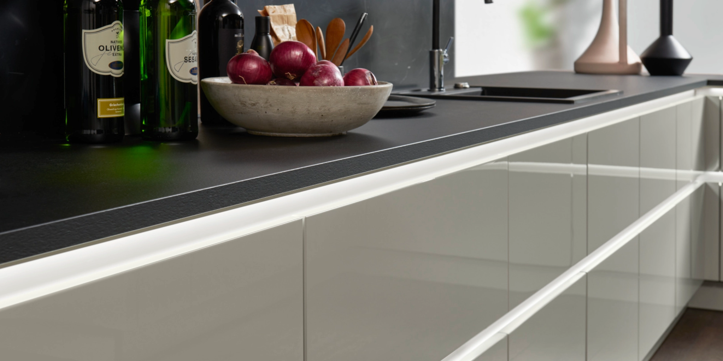 Eine moderne Küche mit schwarzen Arbeitsflächen und eleganten weißen Schränken von Nolte Küchen.