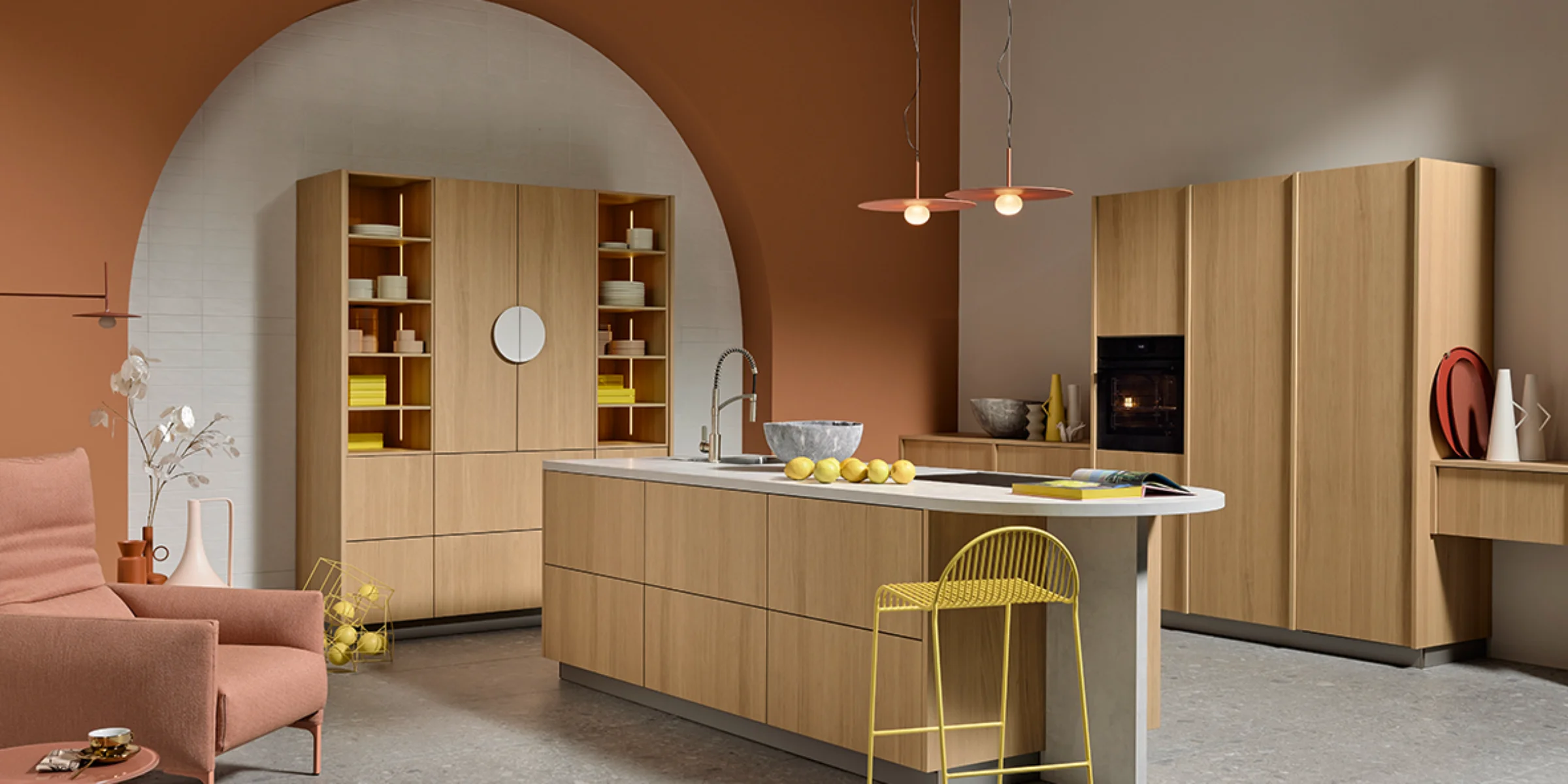 Offene Wohnküche in Eiche Bianco mit Kochinsel, hohen Schränken und harmonischem Farbspiel aus Terrakotta, Gelb und Naturholz. Stylische Beleuchtung und zeitloses Design von nolteneo.