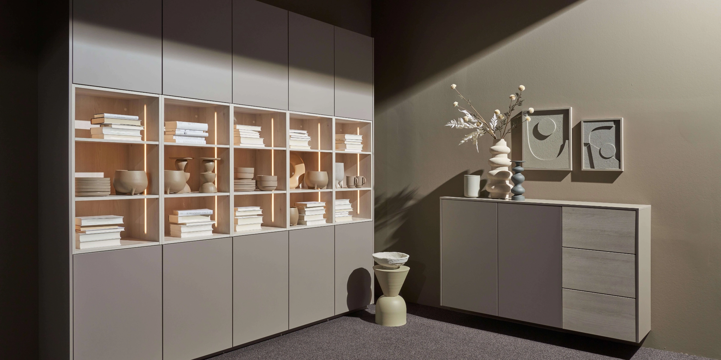Un salon avec étagères et buffet modernes, décoré de vases et de livres, par Nolte Living.