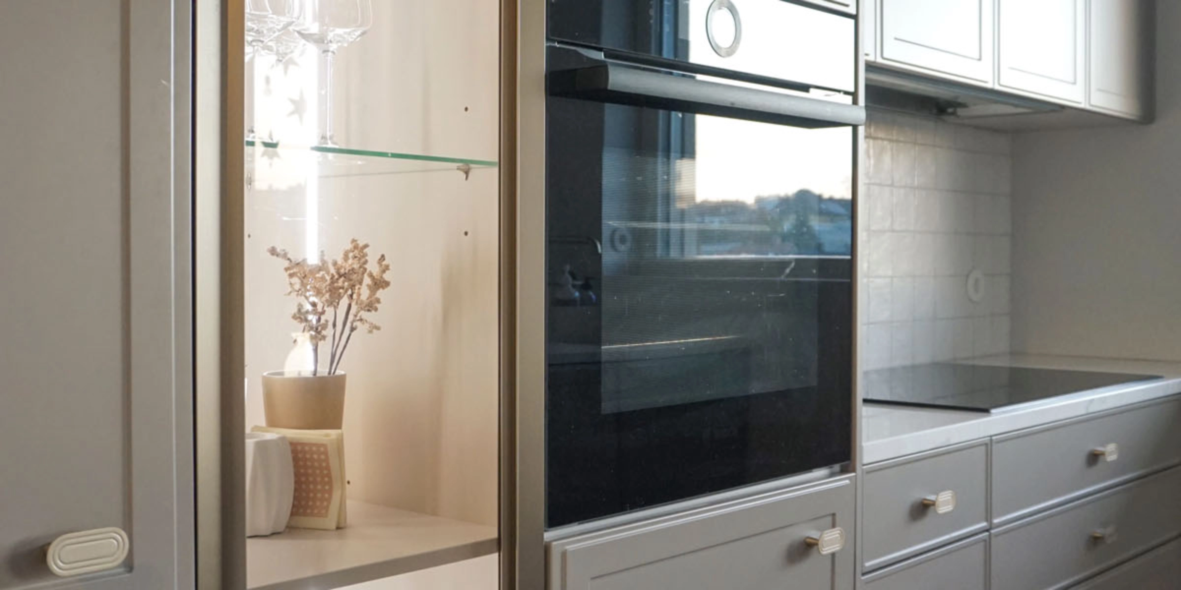 Cuisine moderne avec armoires grises et four encastré, présentée par Nolte Kitchen.