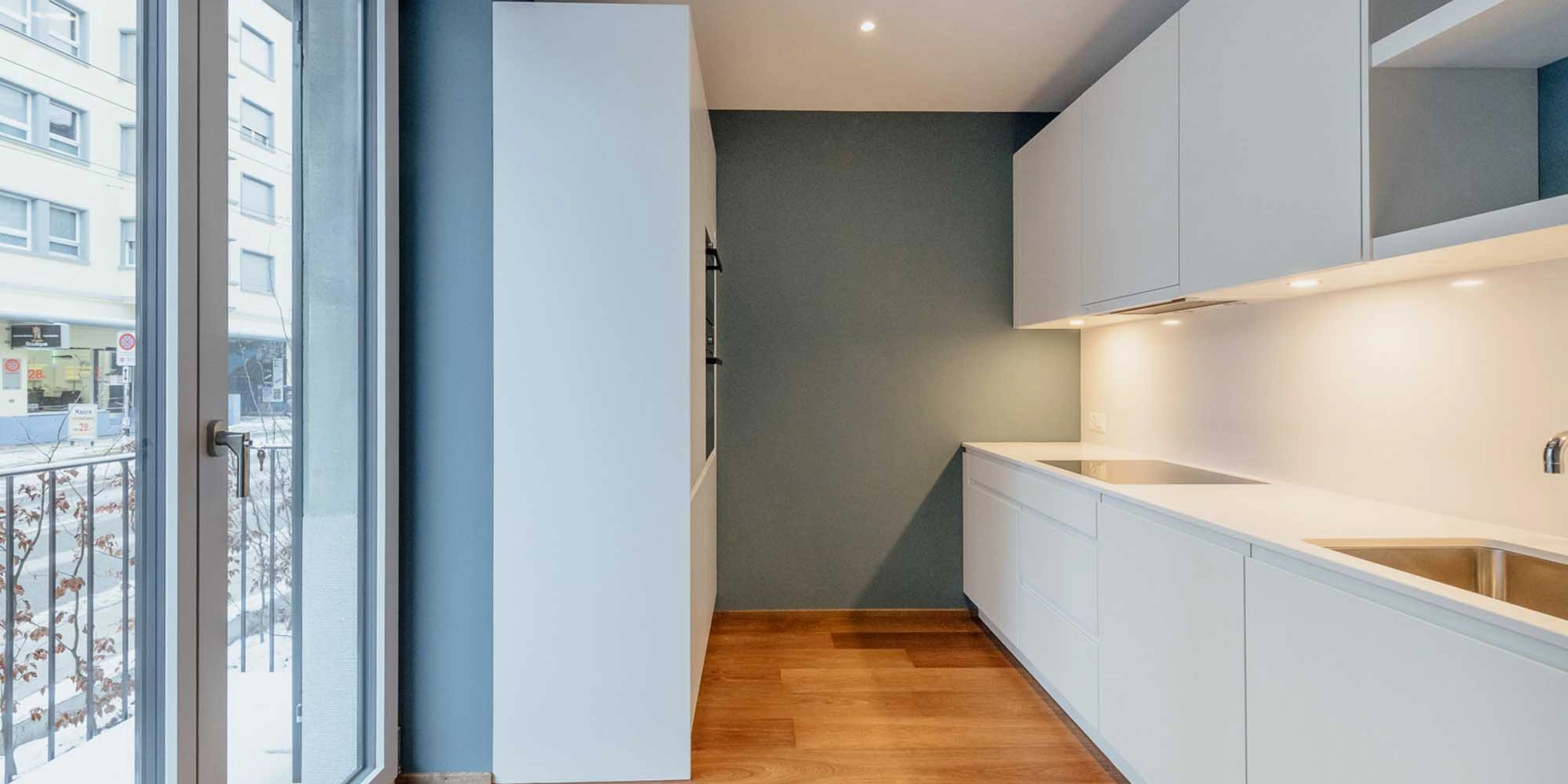 Eine moderne Küche mit weißen Schränken und Holzfußboden, gestaltet von Nolte Küchen.