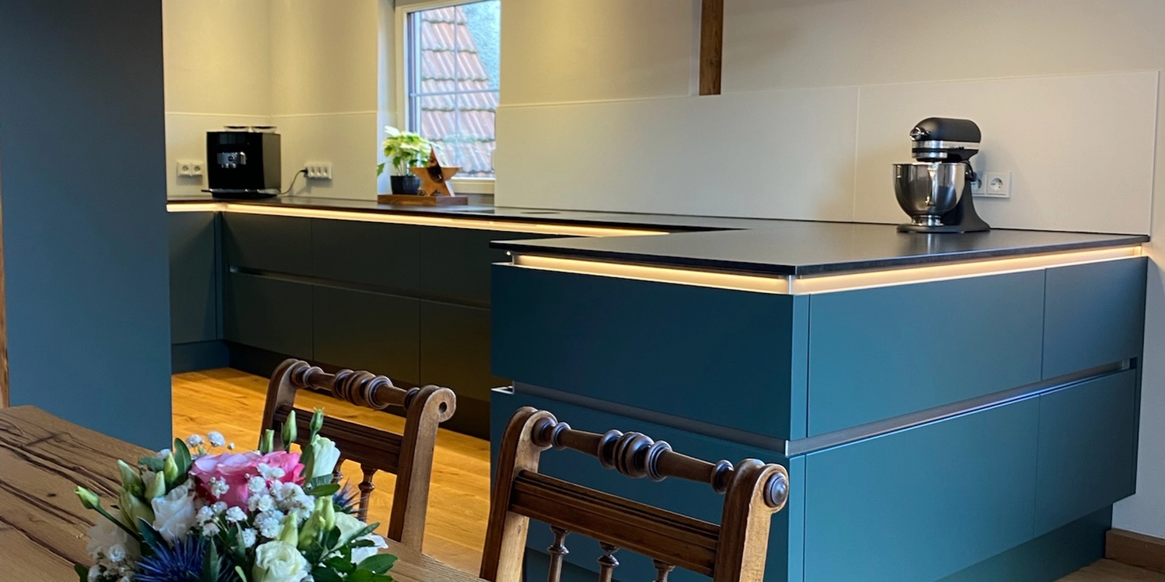 Cuisine moderne avec poutres en bois et fleurs sur la table, conçue par Nolte Kitchen.