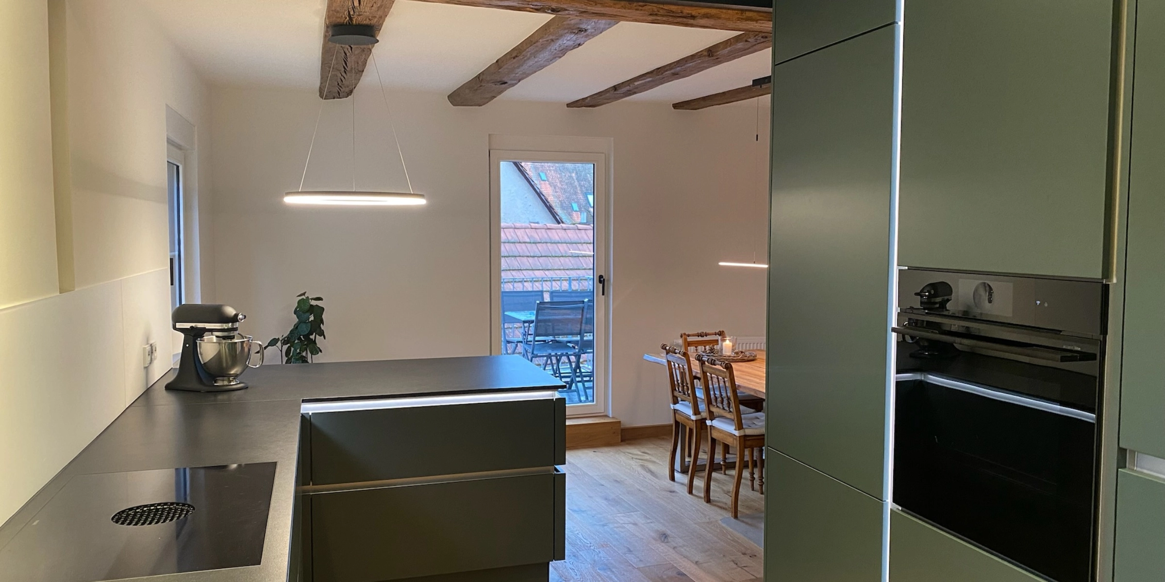 Cuisine moderne avec détails en bois et coin repas, présentée par Nolte Kitchen.