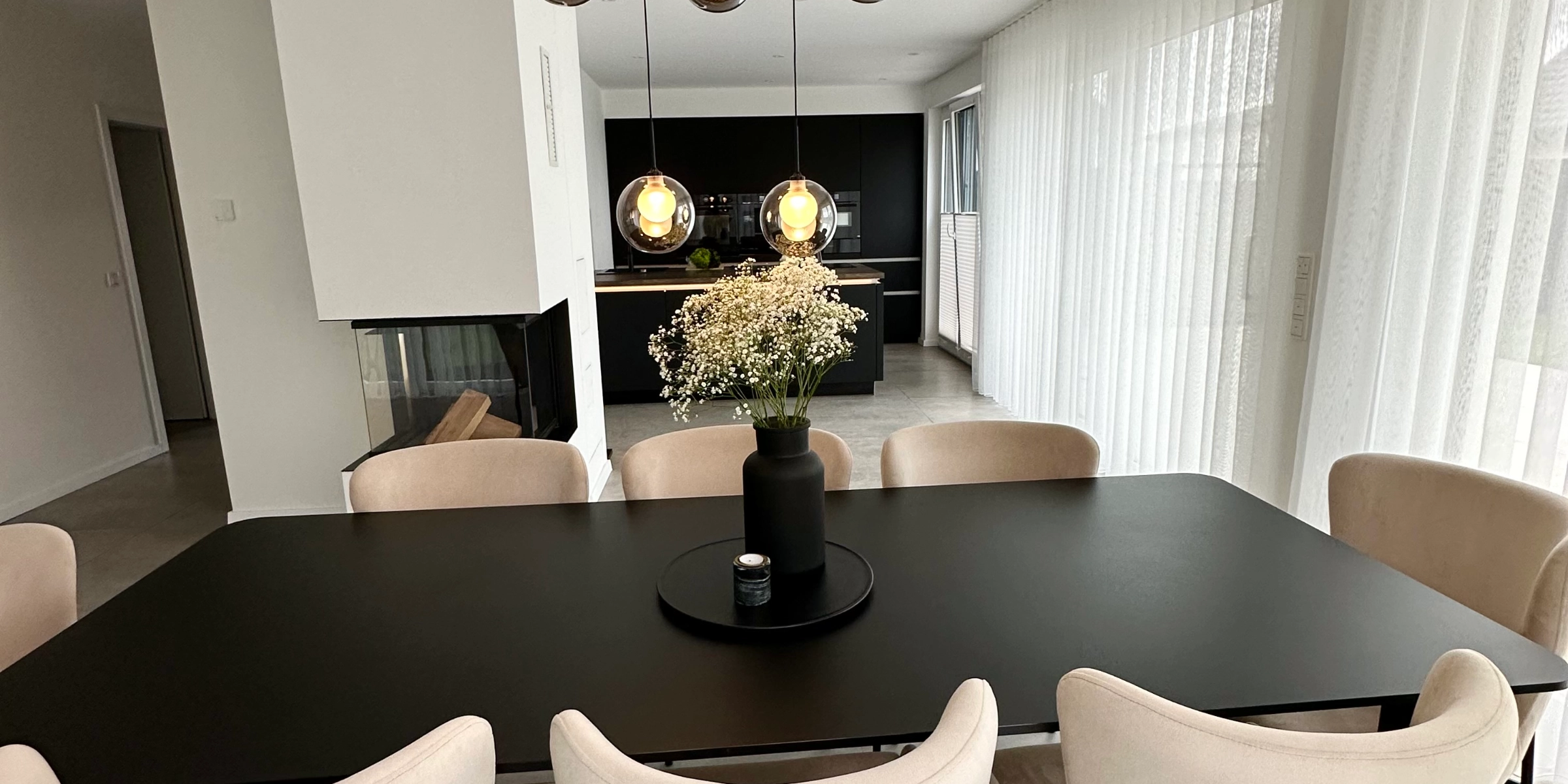 An elegant dining room with a modern table and chairs, highlighted by stylish lighting, by Nolte Living.
