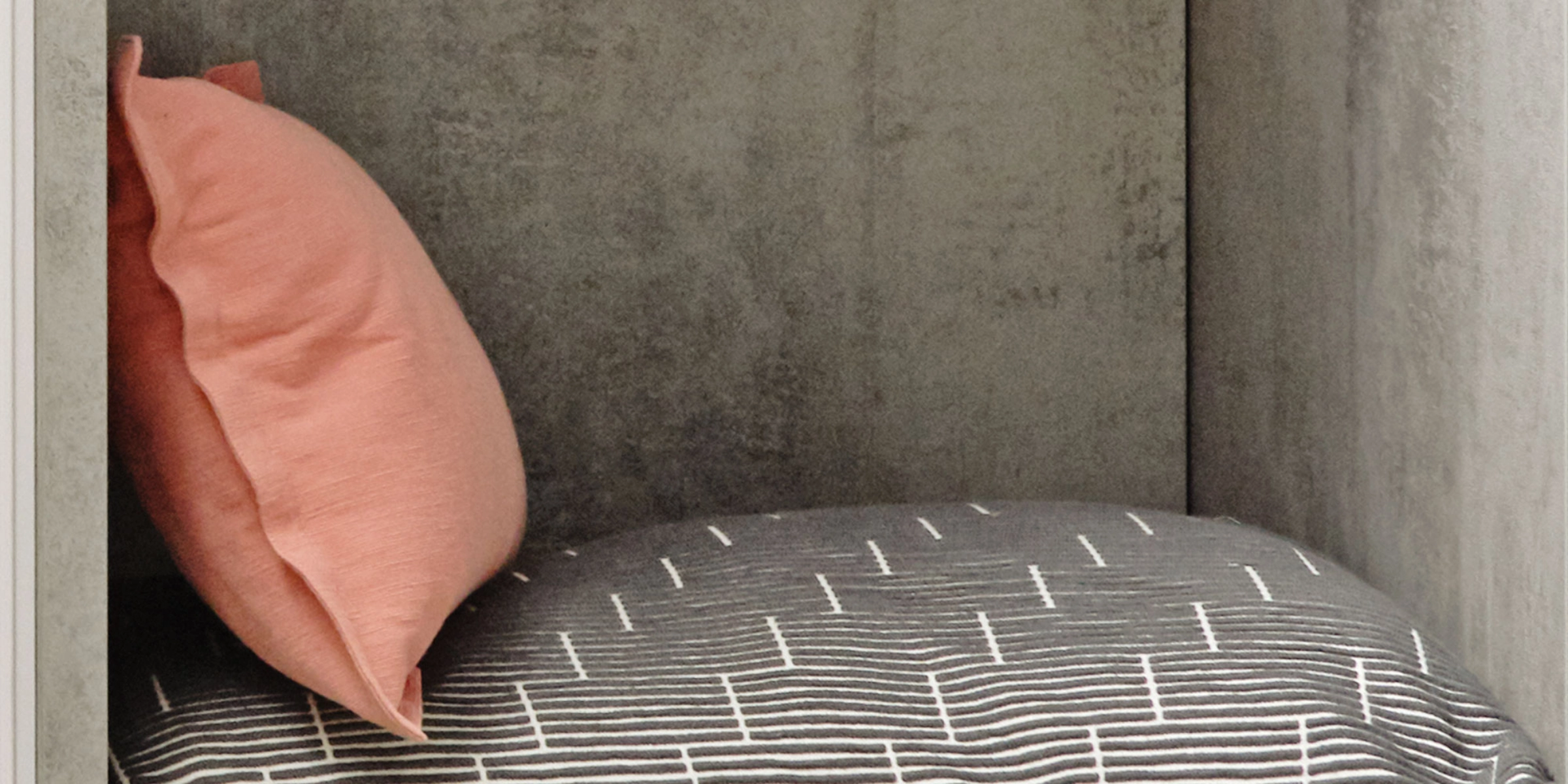 Un coussin gris à rayures blanches et un coussin rose sur une étagère. Nolte Living.