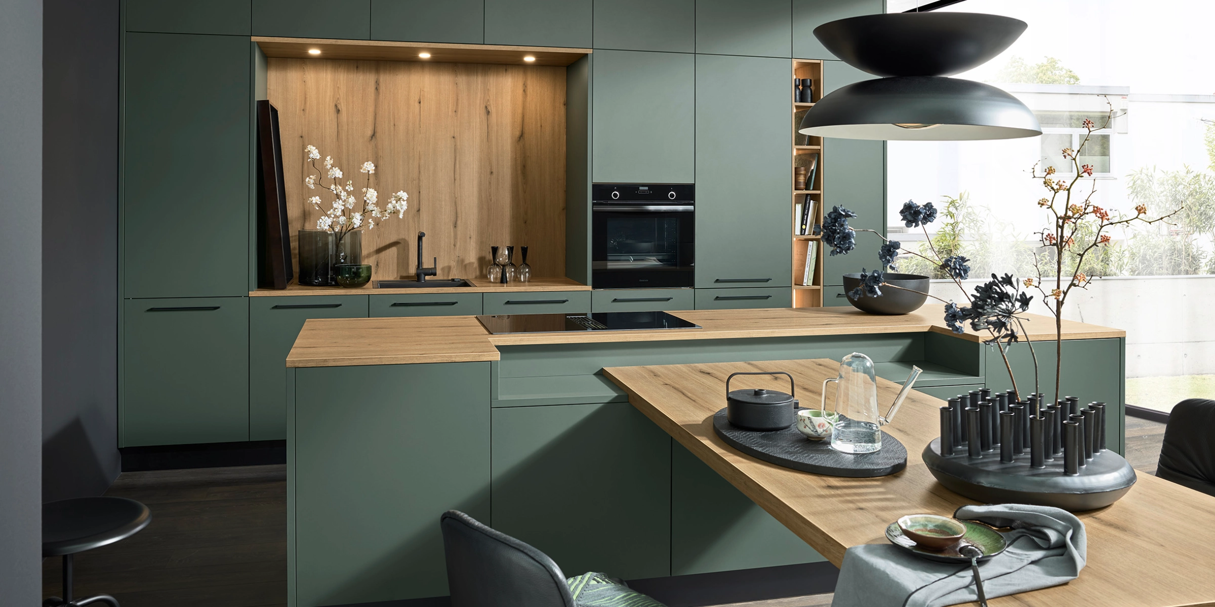 Une cuisine moderne avec des armoires vertes et des détails en bois, conçue par Nolte Kitchen.