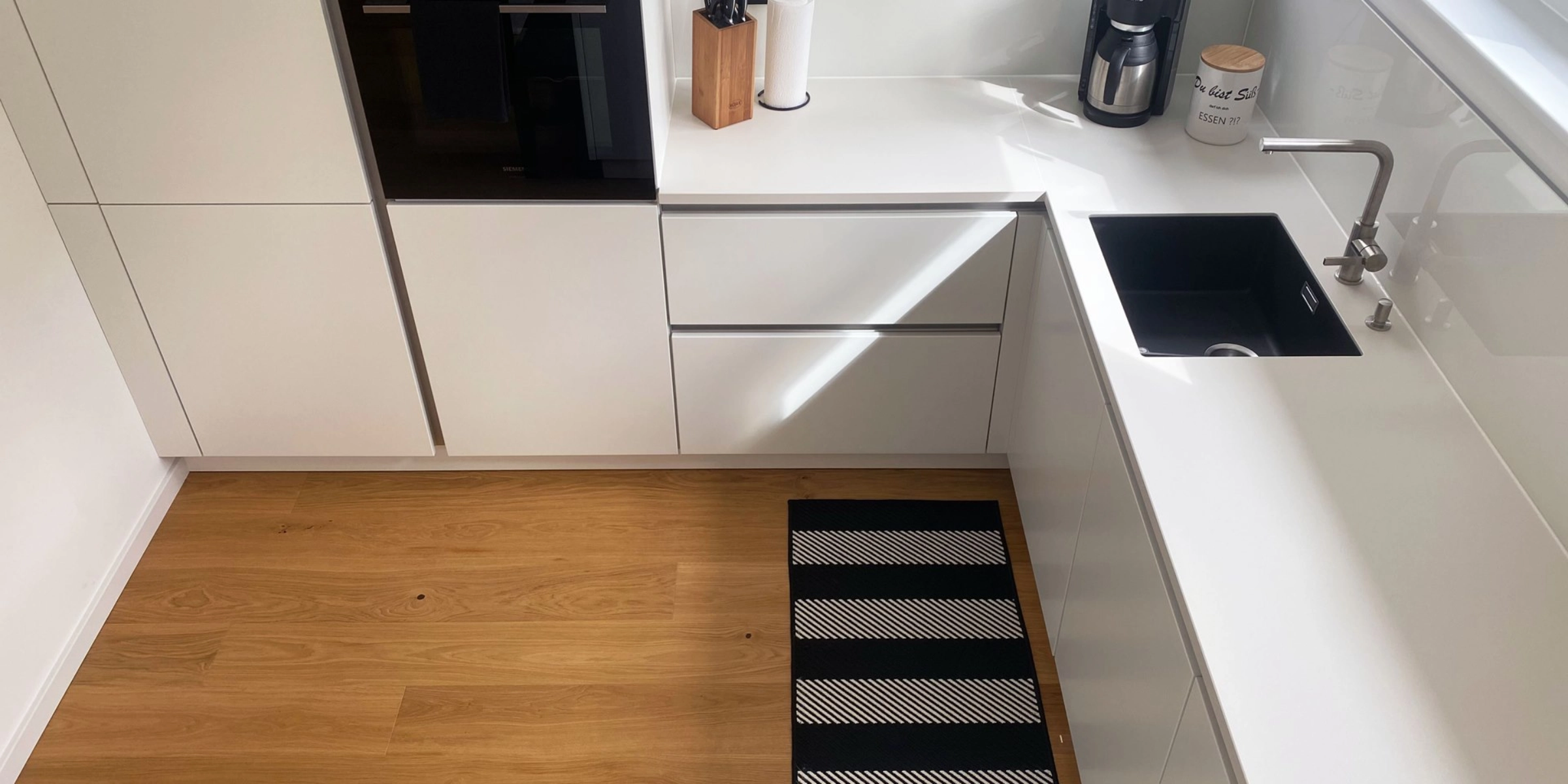 Une cuisine moderne avec des armoires blanches et un sol en bois, Nolte Kitchen.