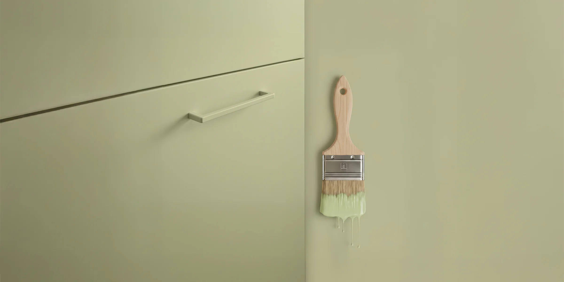 Küchenfront und Wand in Avocado softmatt mit passendem Pinsel – zeigt das harmonische Farbkonzept von Nolte Küchen und SCHÖNER WOHNEN-Farbe.