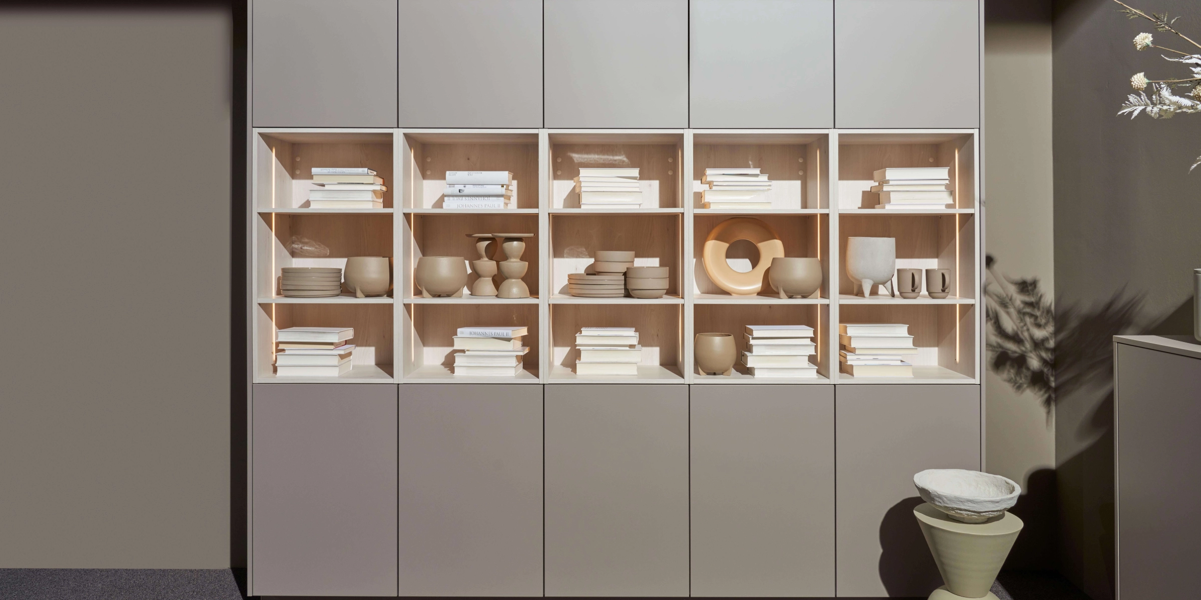 Une étagère avec des vases décoratifs et des livres au design moderne, présentée par Nolte Living.