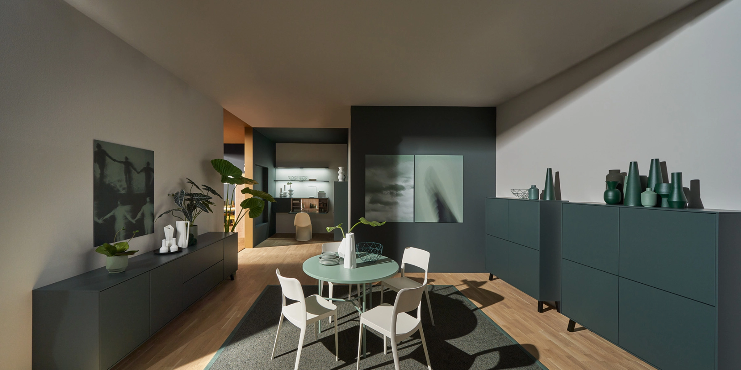Ein modern eingerichtetes Wohnzimmer mit Esstisch und Schränken, dekoriert mit Pflanzen und Kunstwerken, Nolte Living.