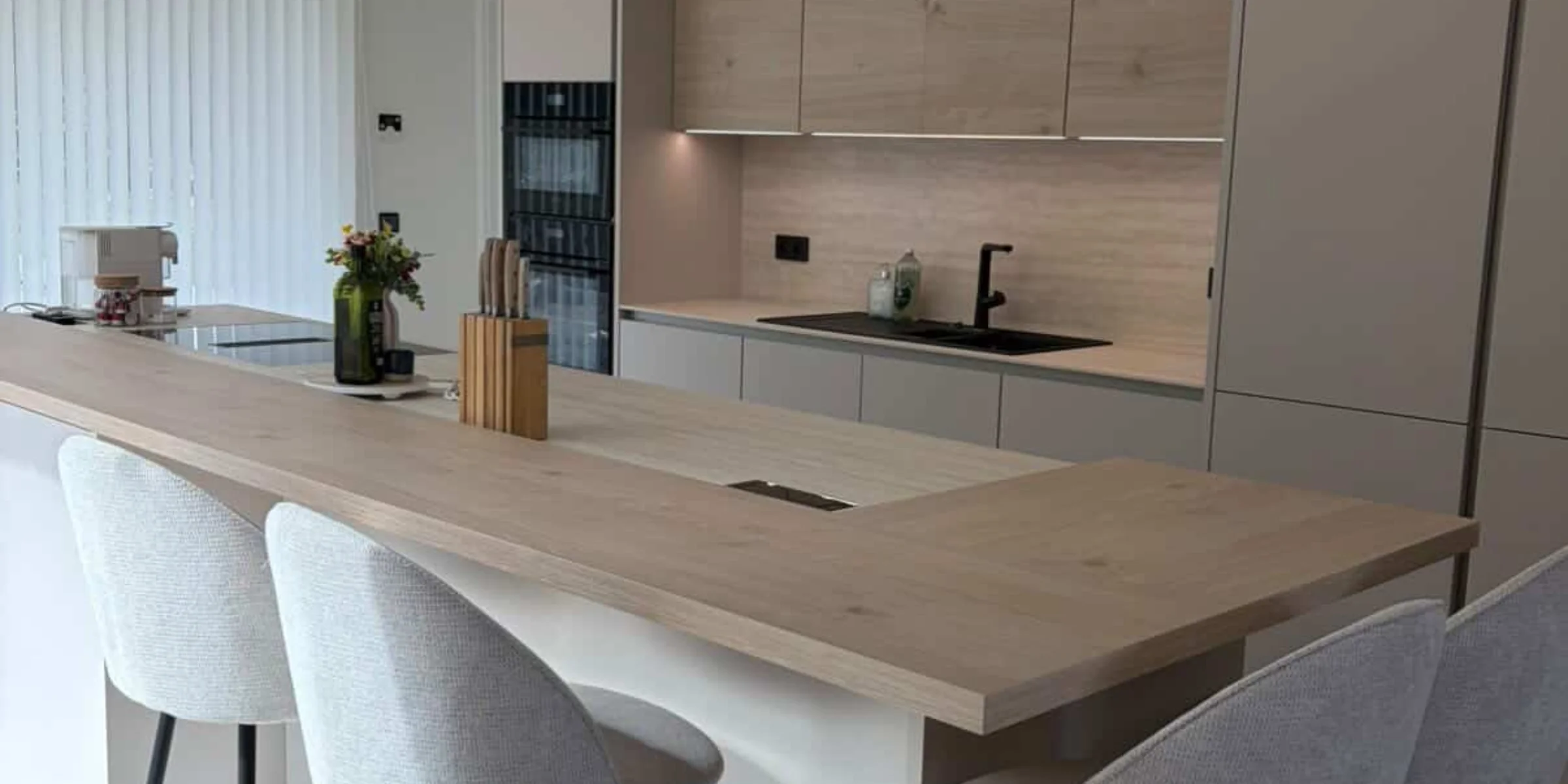 Lichte Nolte-keuken met kookeiland in Sahara Softmatt en houten werkblad in een moderne, open woonkamer