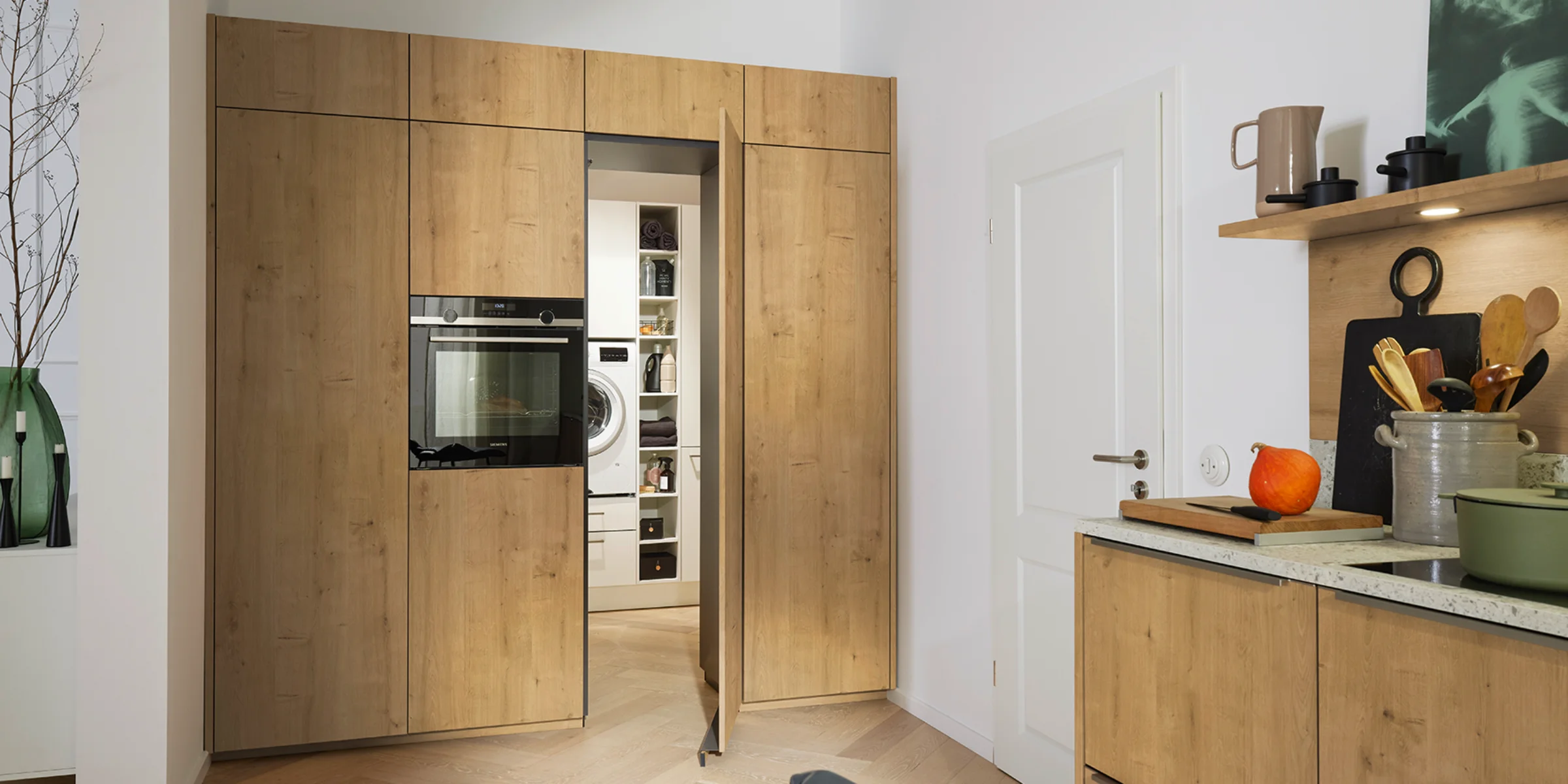 Une buanderie avec armoires en bois et appareils intégrés, partie des buanderies Nolte.