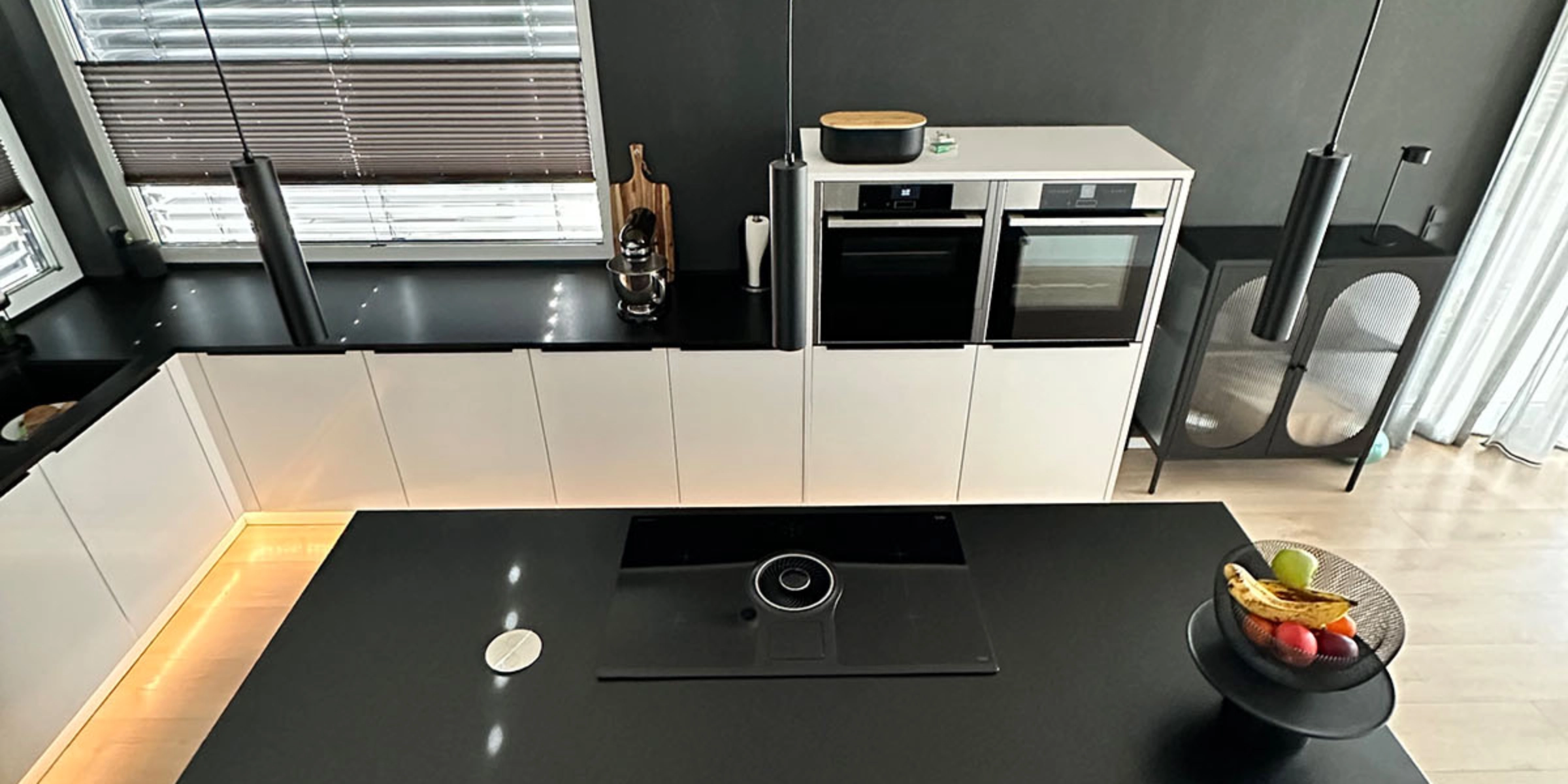Une cuisine moderne avec plan de travail noir et îlot, équipée par Nolte Kitchen.