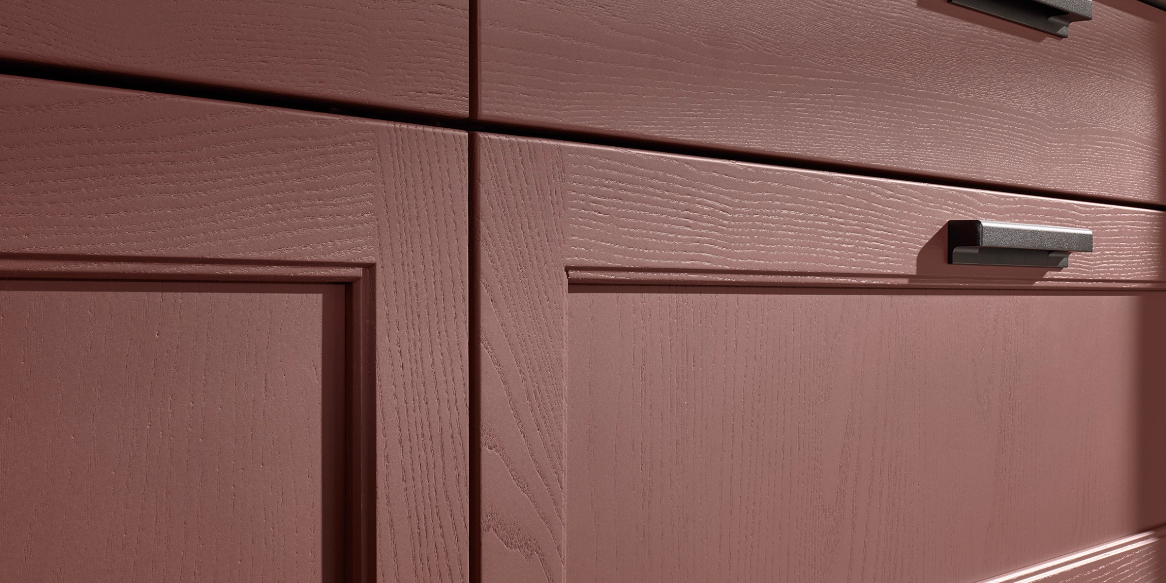 Armoires de cuisine rouges avec texture bois et poignées modernes, design élégant par Nolte Kitchen.