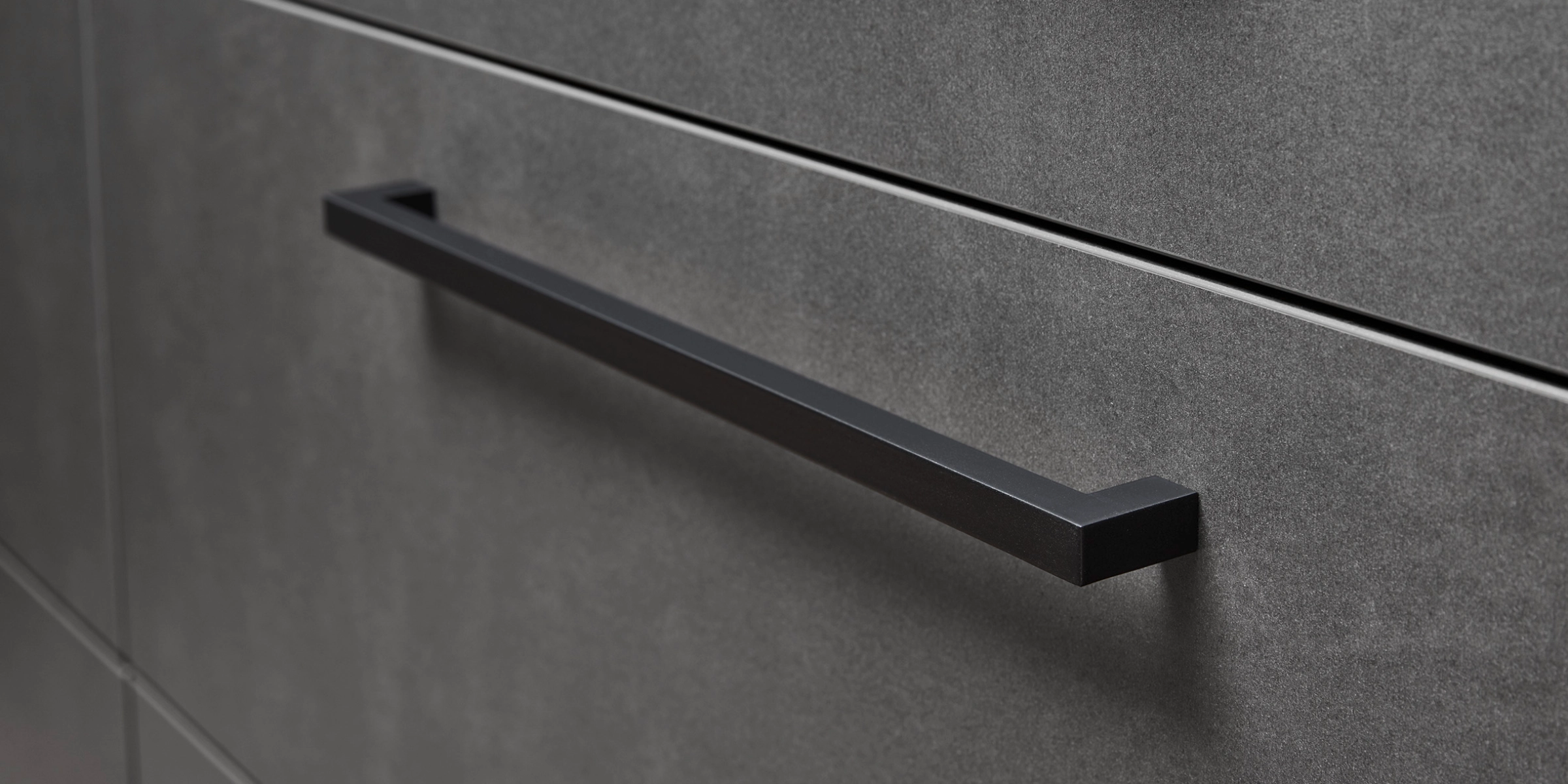 Armoires de cuisine grises avec poignées noires, élégamment conçues par Nolte Kitchen.