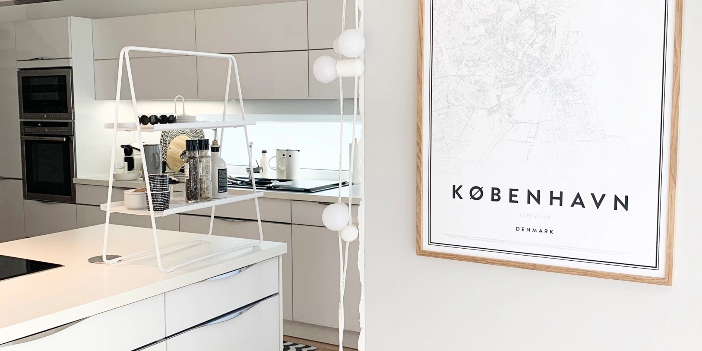 Dans la cuisine moderne avec des armoires blanches, un poster "København" est accroché au mur. Nolte Kitchen.
