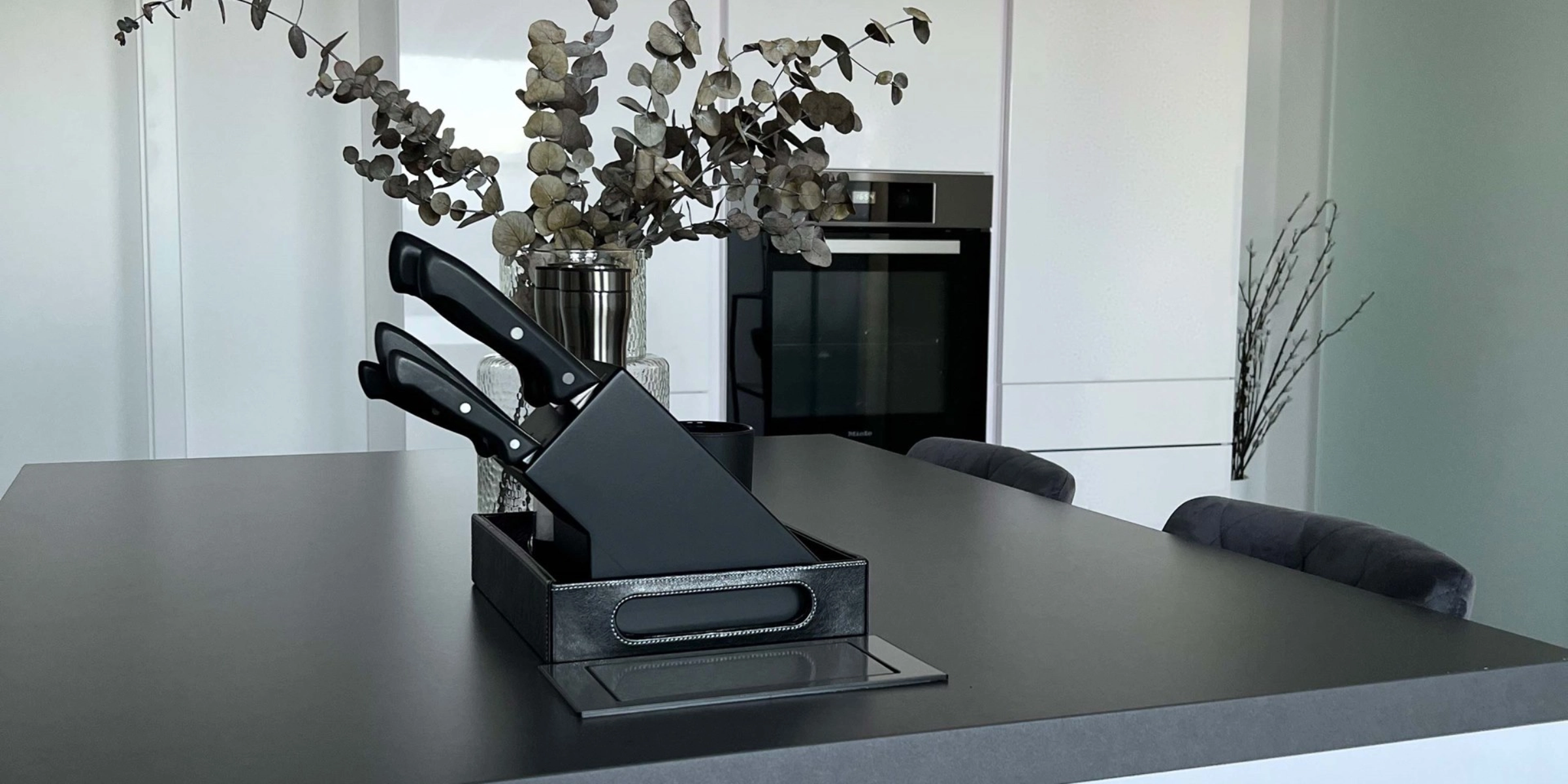 Cuisine moderne avec îlot, armoires blanches, décorée de plantes. Nolte Kitchen.