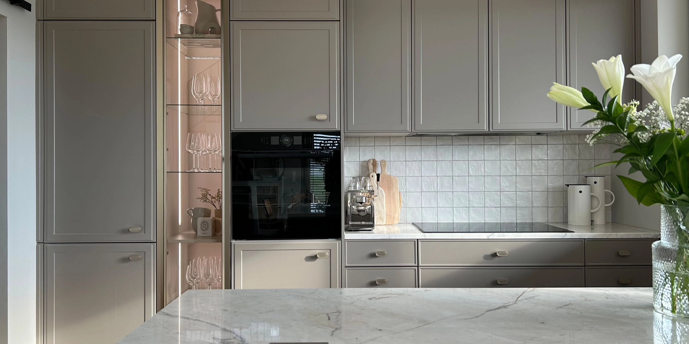 Cuisine moderne avec armoires grises et îlot en marbre de la collection Nolte Kitchen.