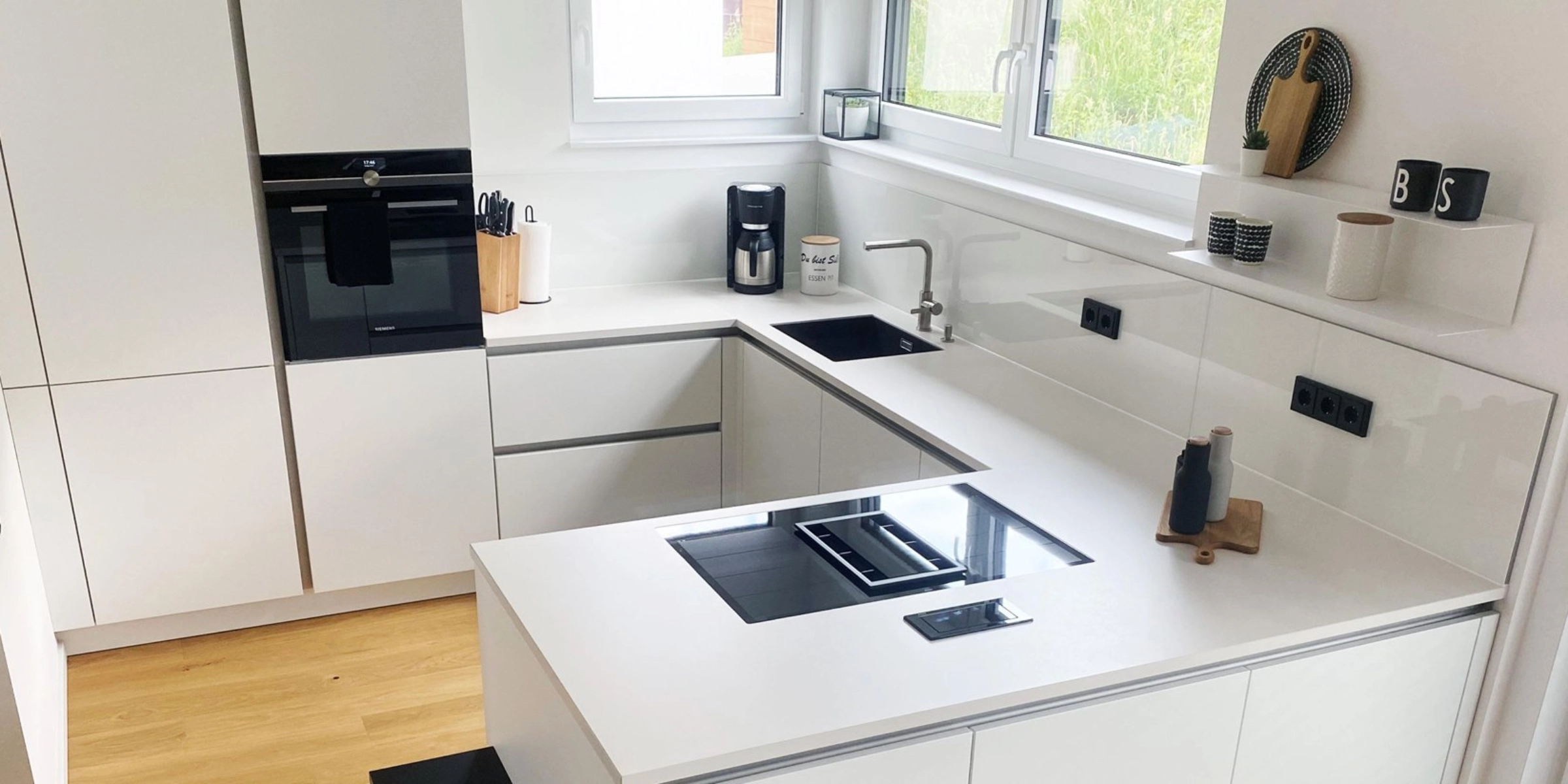 Cuisine moderne blanche avec appareils intégrés et évier d'angle, conçue par Nolte Kitchen.
