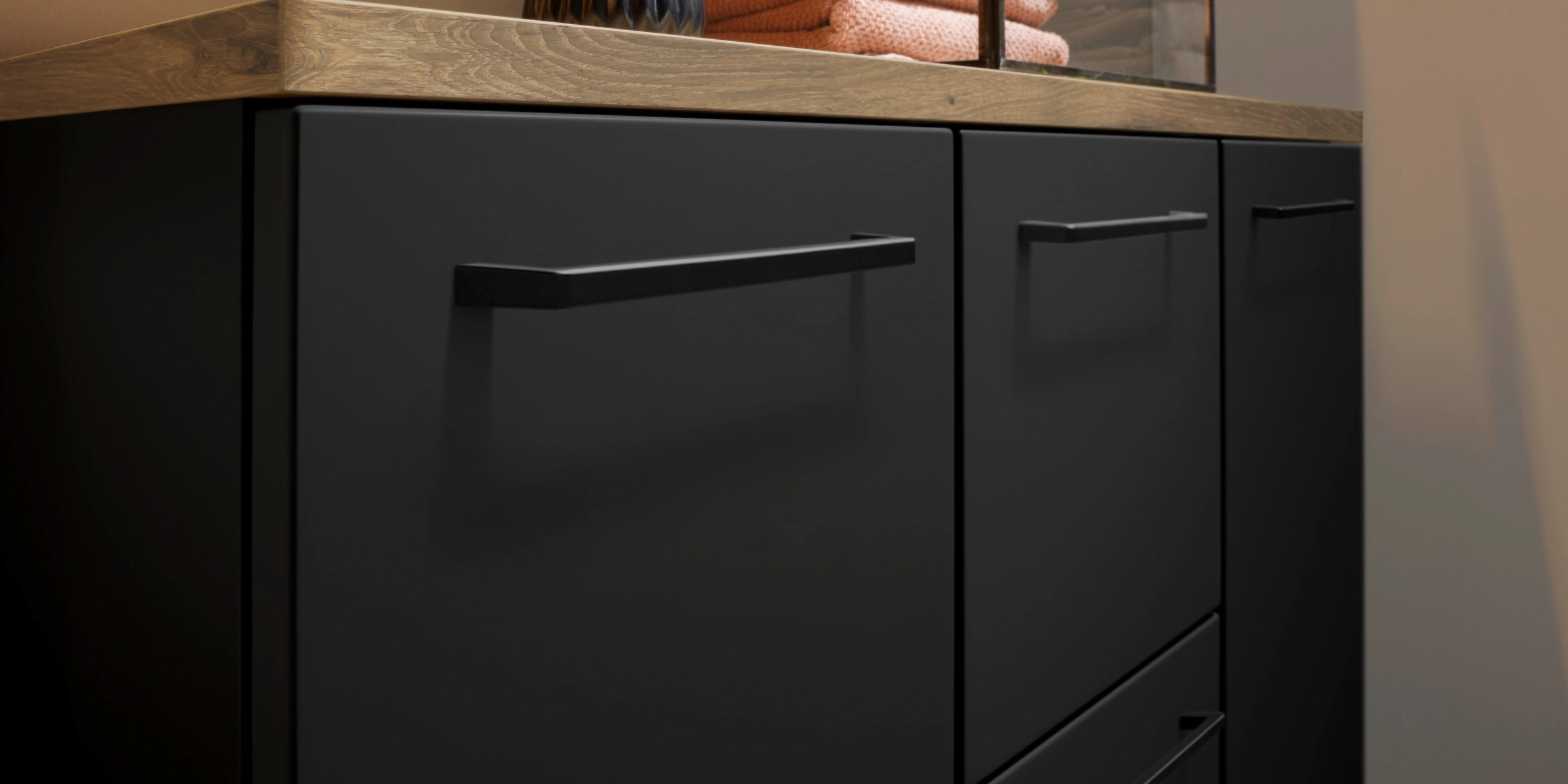 Elegante zwarte kast met houten blad en decor, passend bij Nolte Living.