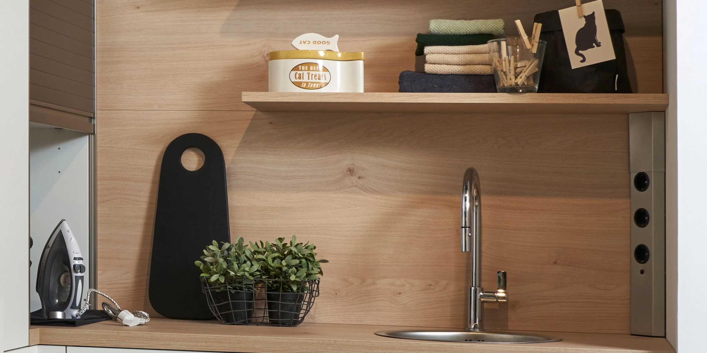 Une cuisine moderne avec étagères en bois et évier, décorée de plantes et accessoires. Nolte Kitchen.
