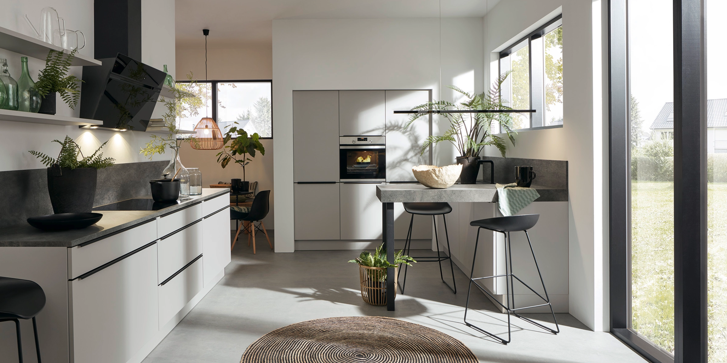 Cuisine moderne avec îlot central et grandes fenêtres, conçue par Nolte Kitchen.