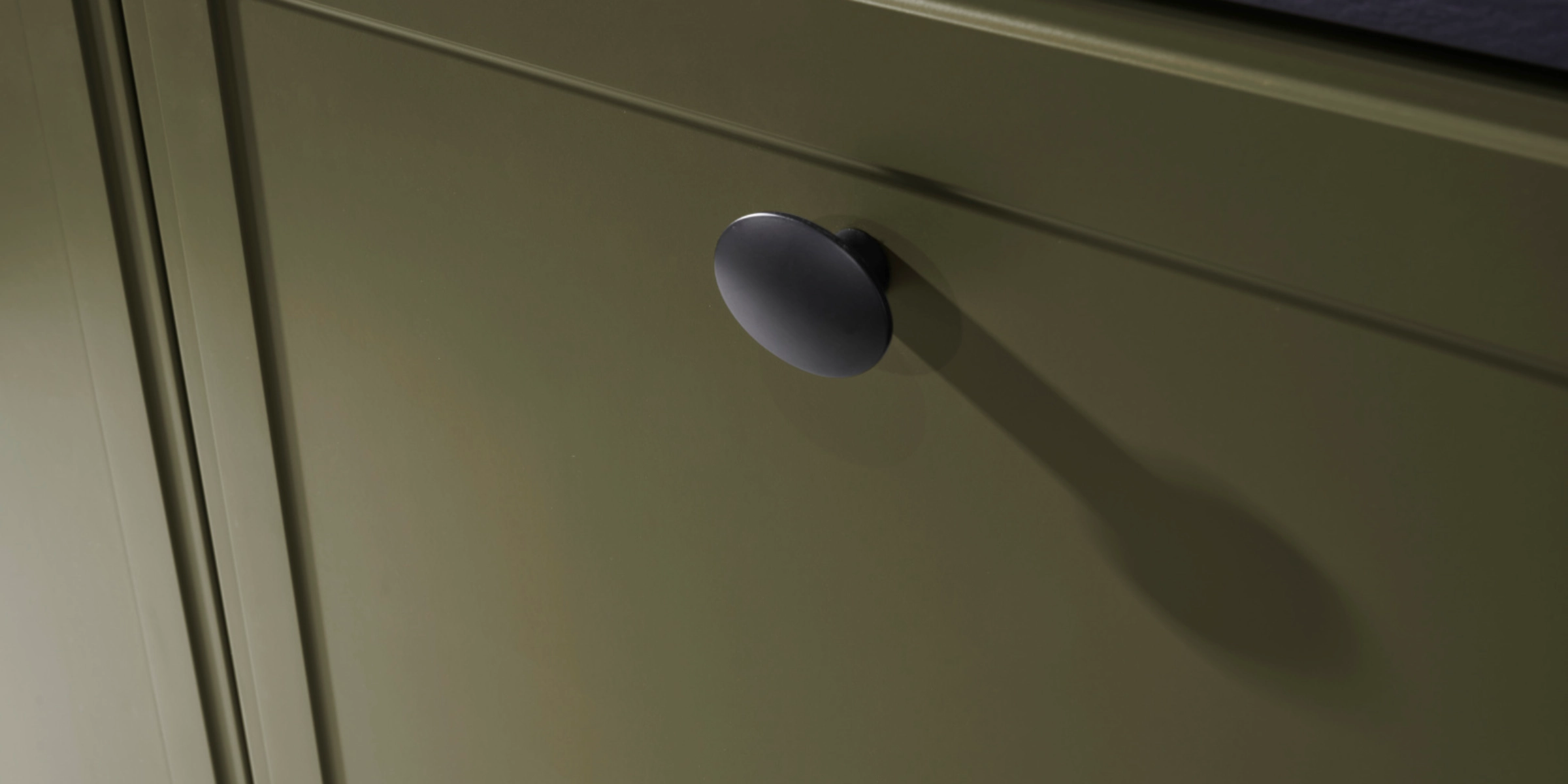 Un placard de cuisine vert avec un bouton noir, partie de Nolte Kitchen.