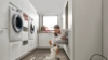 Une femme joue avec un chien dans une buanderie moderne de Nolte Utility Rooms.