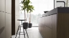 Cuisine moderne avec îlot et tabourets, plantes devant une grande fenêtre. Nolte Kitchen.