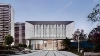 Ein modernes Gebäude mit Glasfront und umliegender Gartenlandschaft bei Tageslicht.