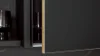 Moderne nolte Küchen Front FLAIR in Schwarz softmatt mit eleganter Messingkante, kombiniert mit warm beleuchtetem Rückwandpaneel und dunkler Arbeitsplatte.