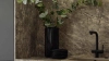 A stylish kitchen with marble look, black faucet, and green plants. Nolte Kitchen.