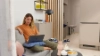 A woman sits on a sofa with a laptop in a modern living room, surrounded by stylish Nolte Living decor.