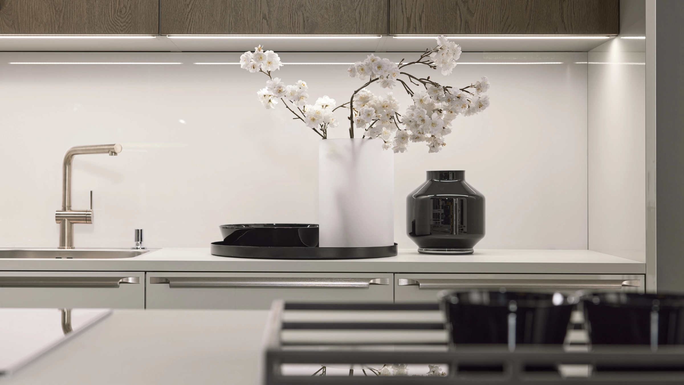 Una encimera de cocina moderna con decoración floral y grifería elegante, Nolte Cocina.