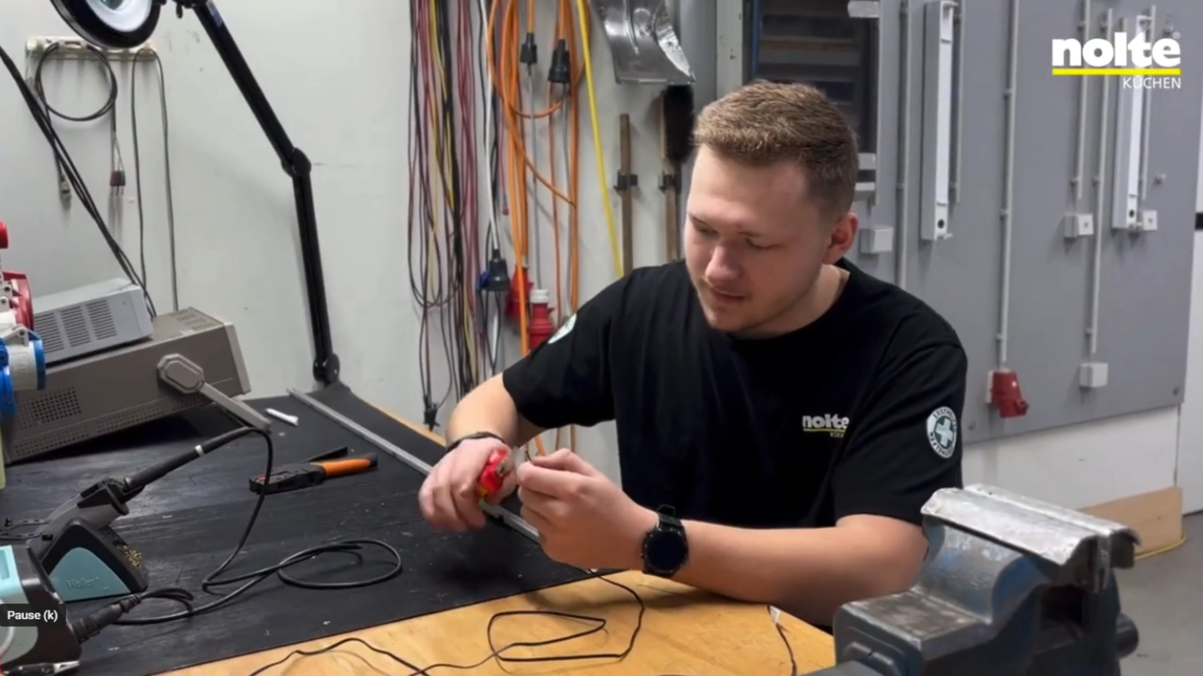 Ein Mann arbeitet in einer Werkstatt mit elektronischen Geräten, Nolte Küchen.